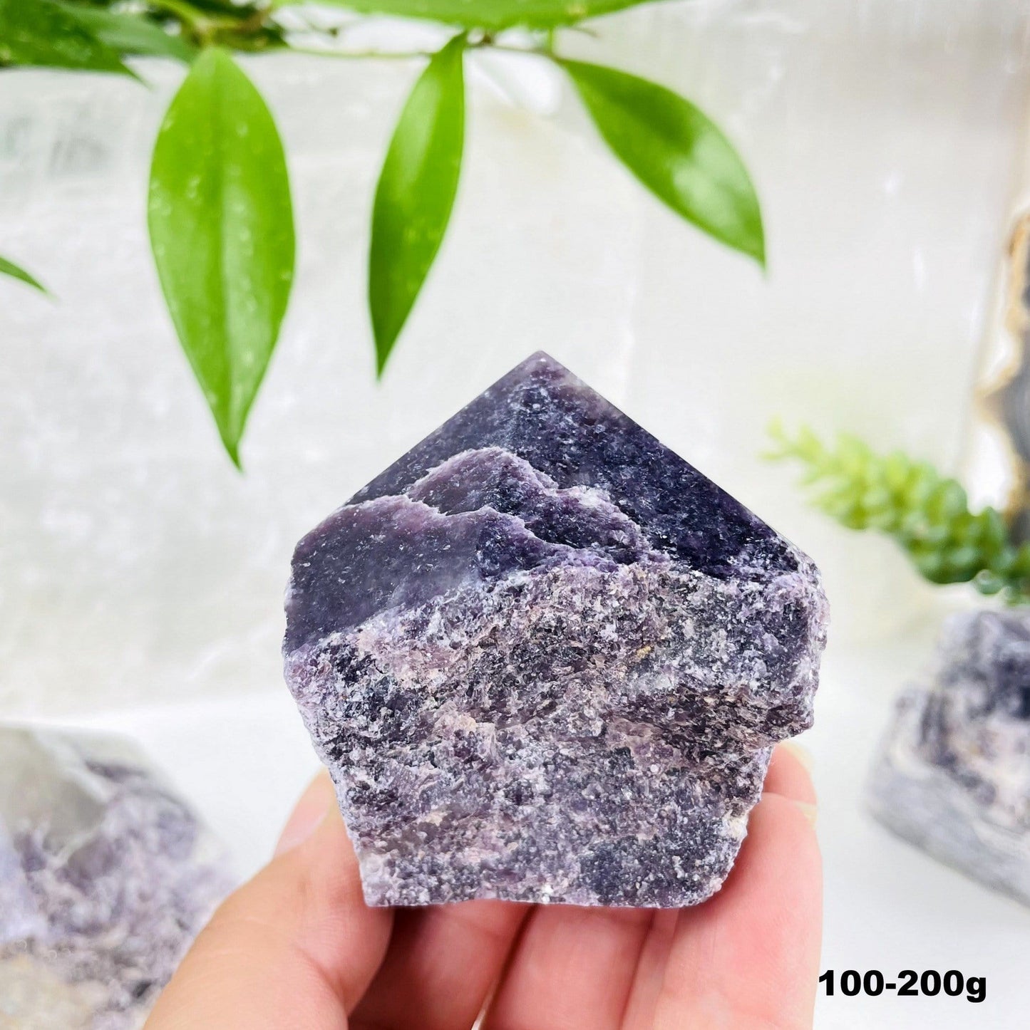 lepidolite semi polished point with decorations in the background