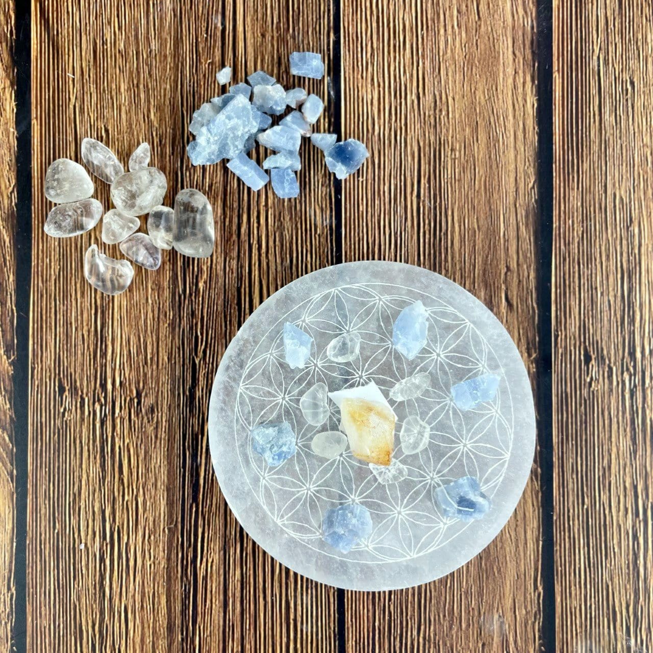 overhead close up of selenite round plate engraved with flower of life with charging stones