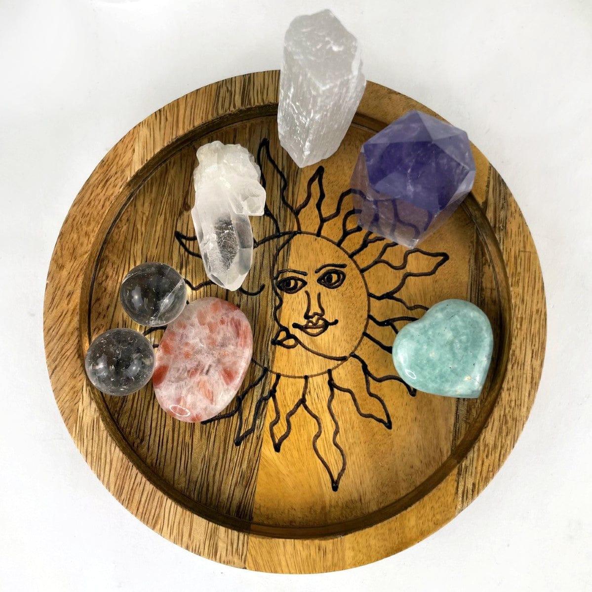close up of small ound Mango wood tray with a sun and moon etched in black inside.  Assorted crystals are placed in the tray for decoration