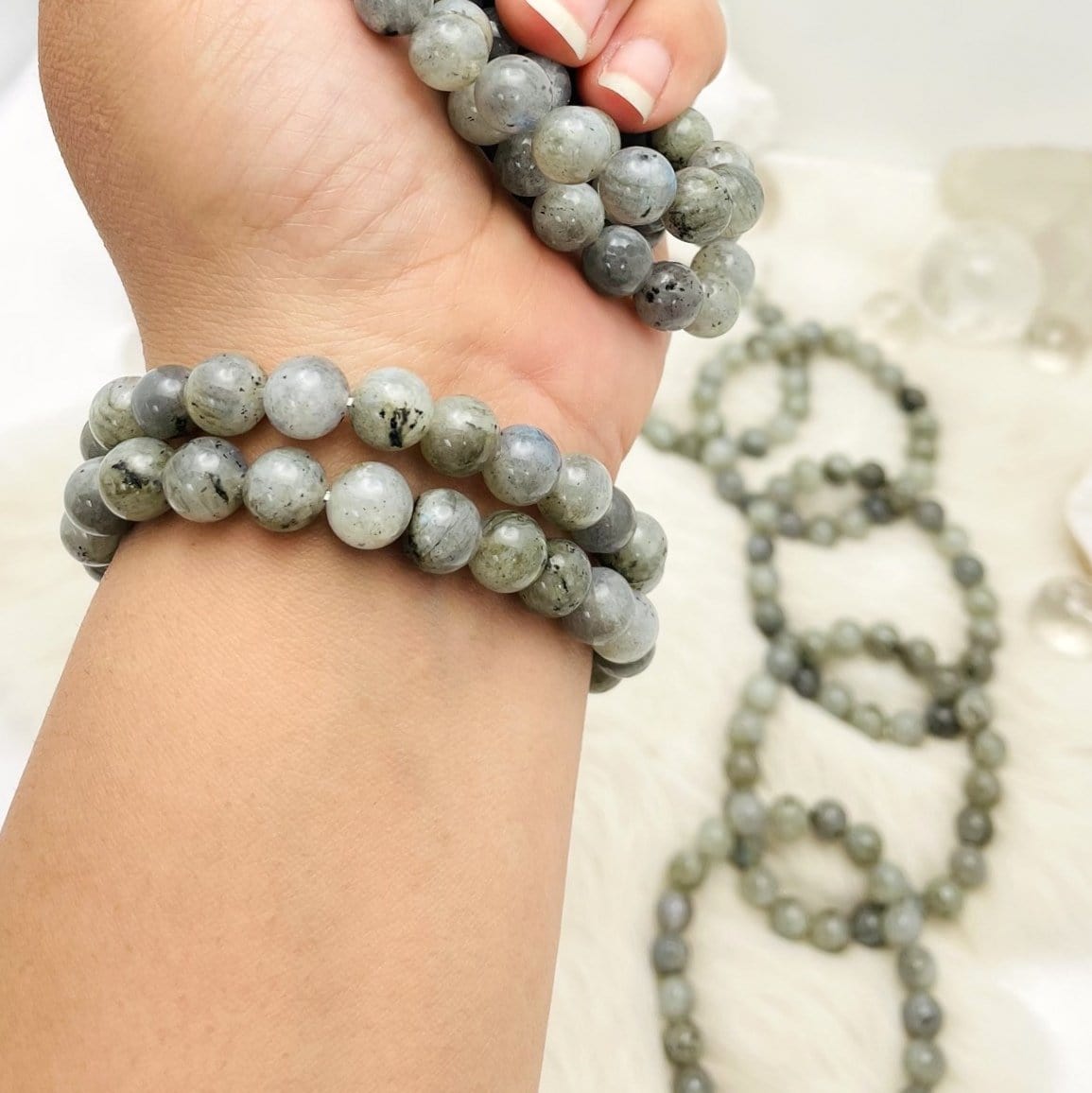 wrist wearing labradorite bracelets with others in the background