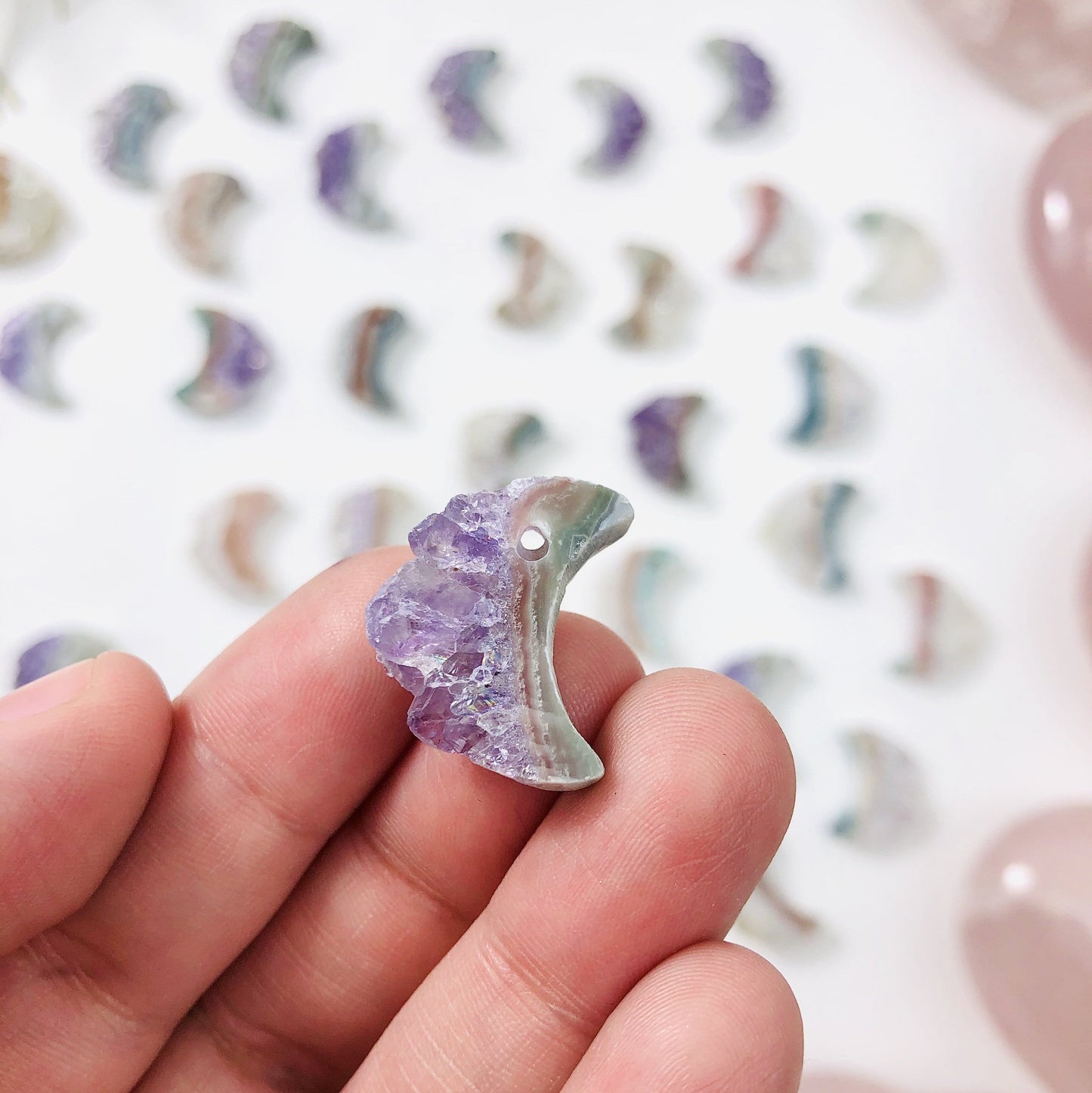 hand holding up amethyst moon crescents with decorations in the background