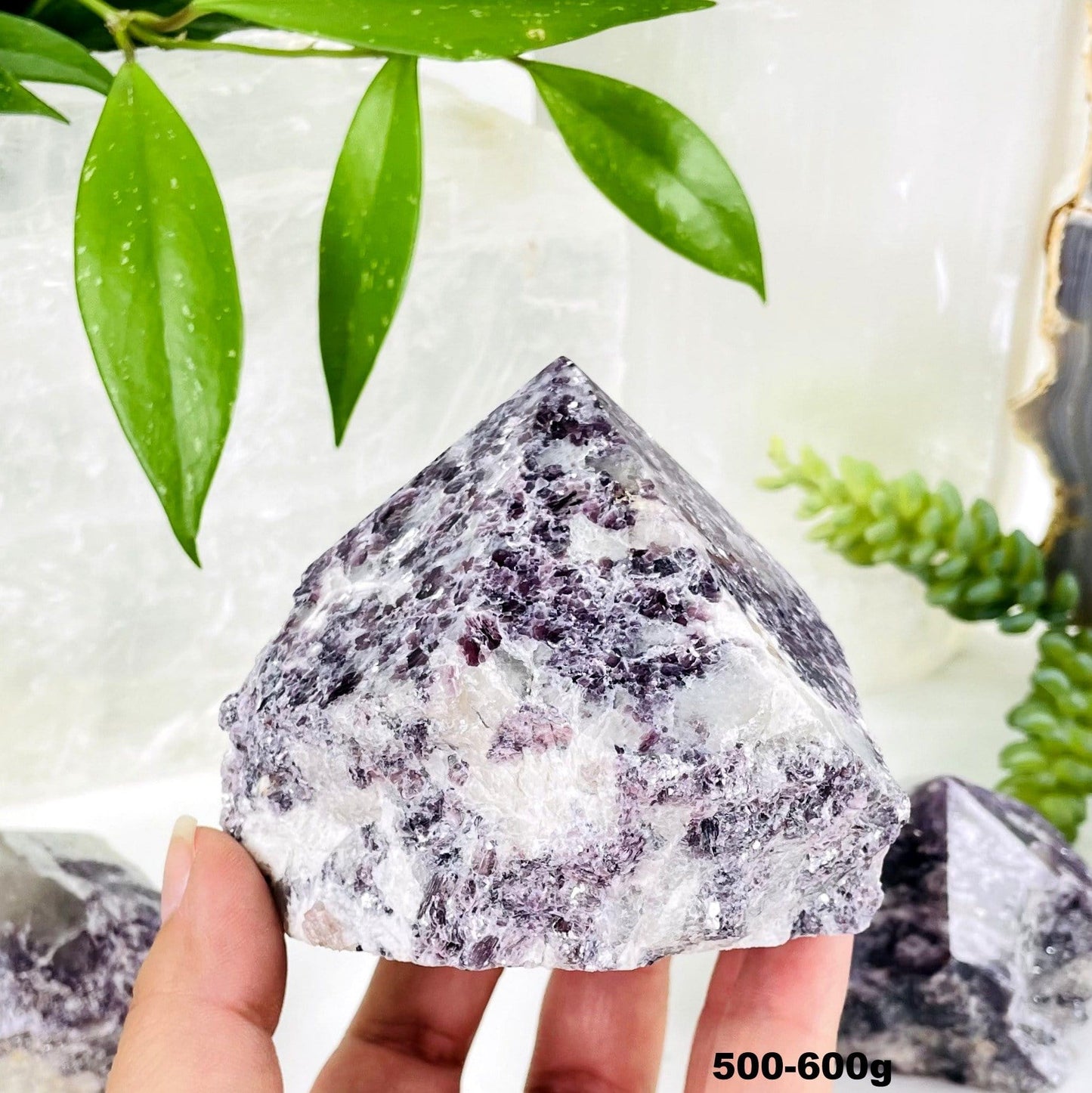 lepidolite semi polished point with decorations in the background
