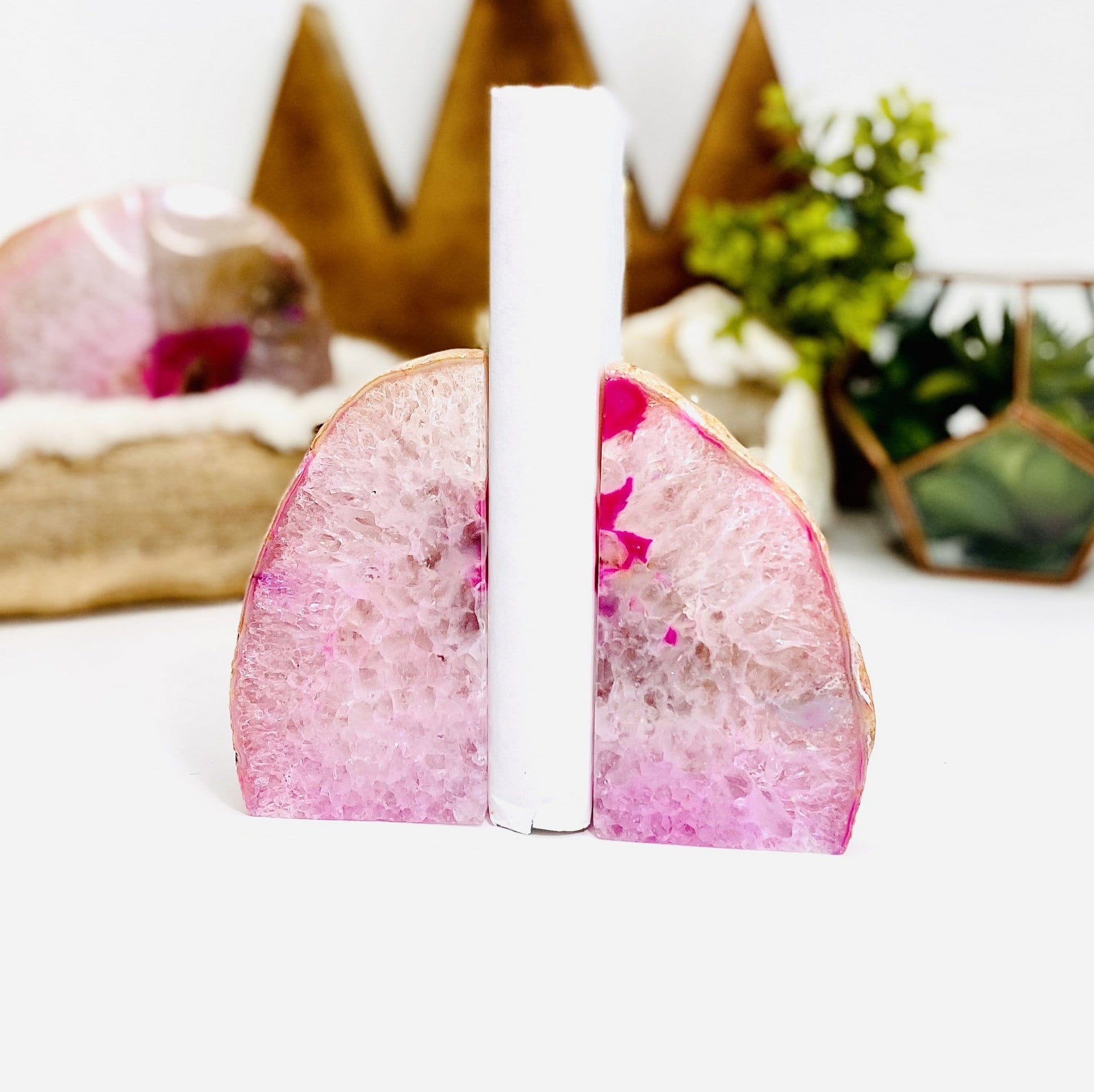 Pink Agate Geode Bookend Pair pictured with a book held up secure between them.