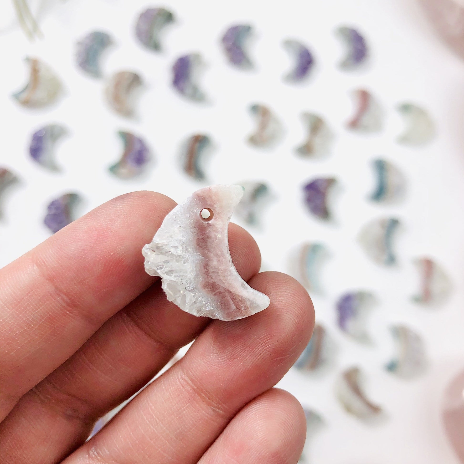 hand holding up amethyst moon crescent with more in the background