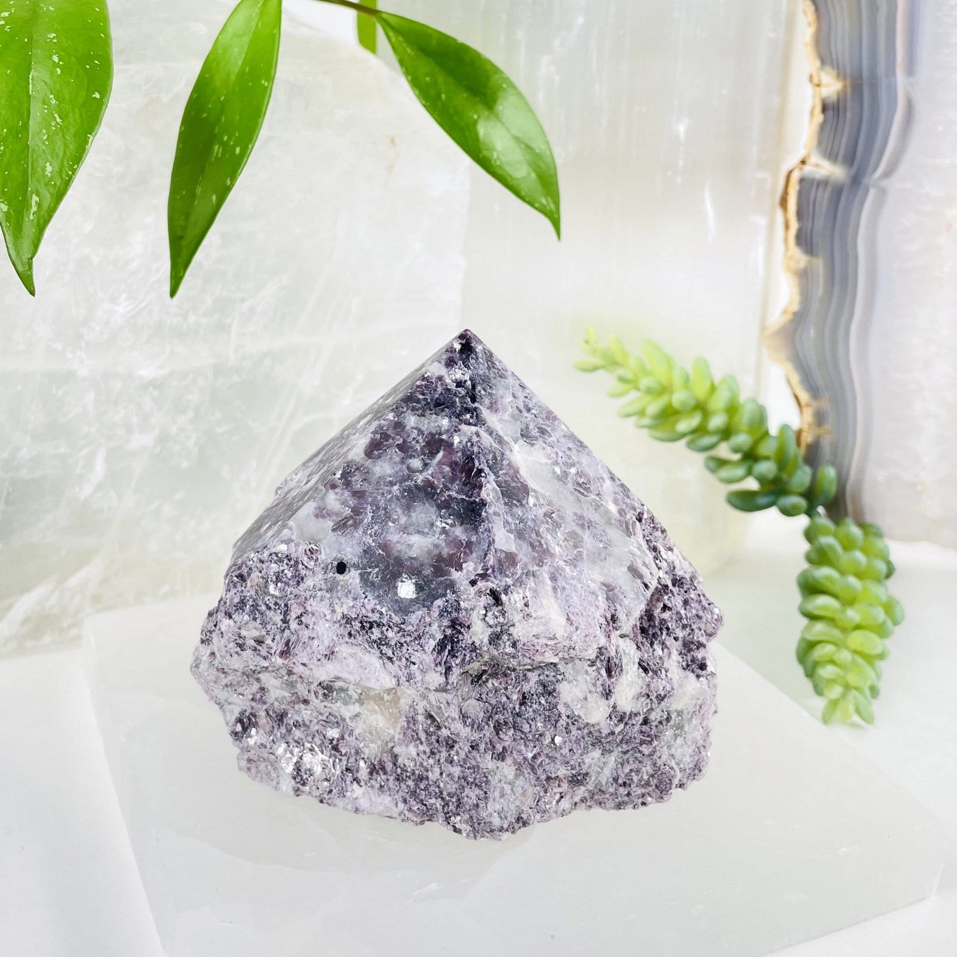 lepidolite semi polished point with decorations in the background