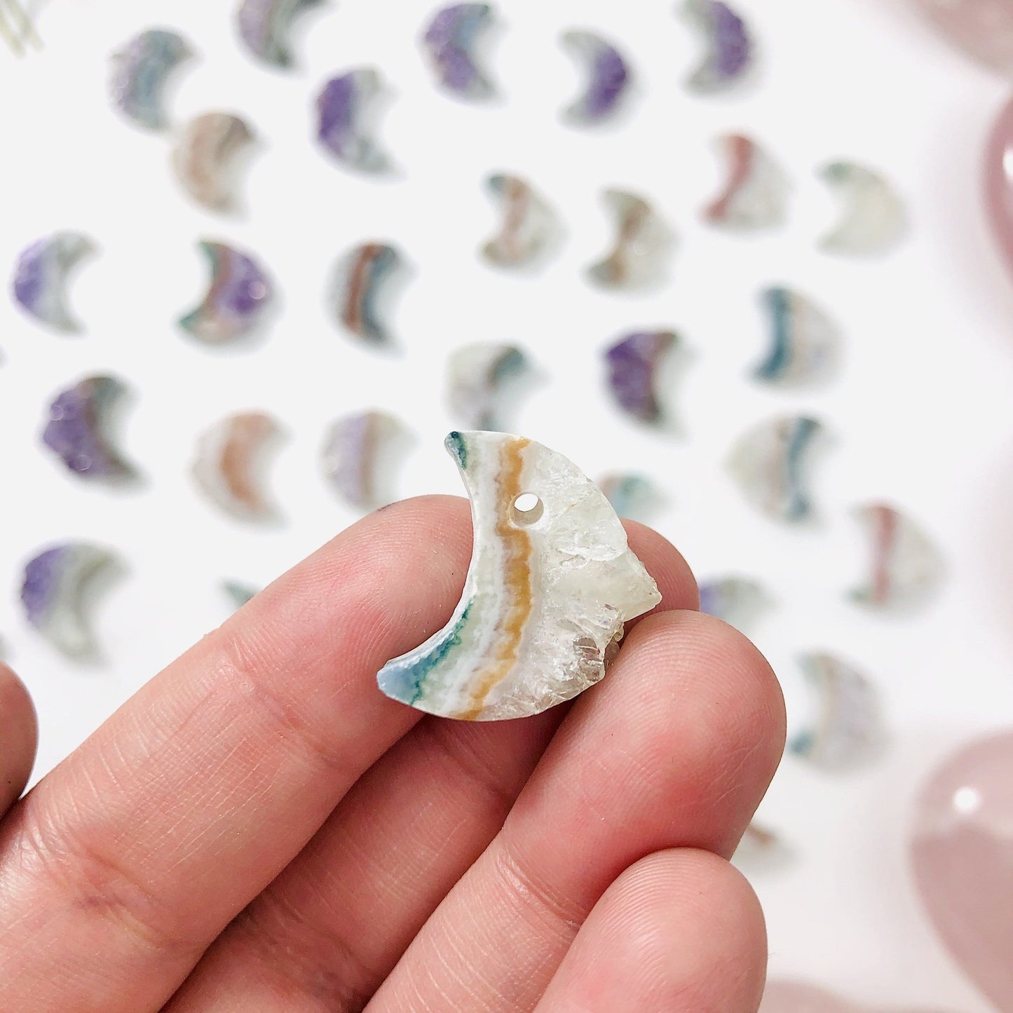 hand holding up amethyst moon crescents with decorations in the background