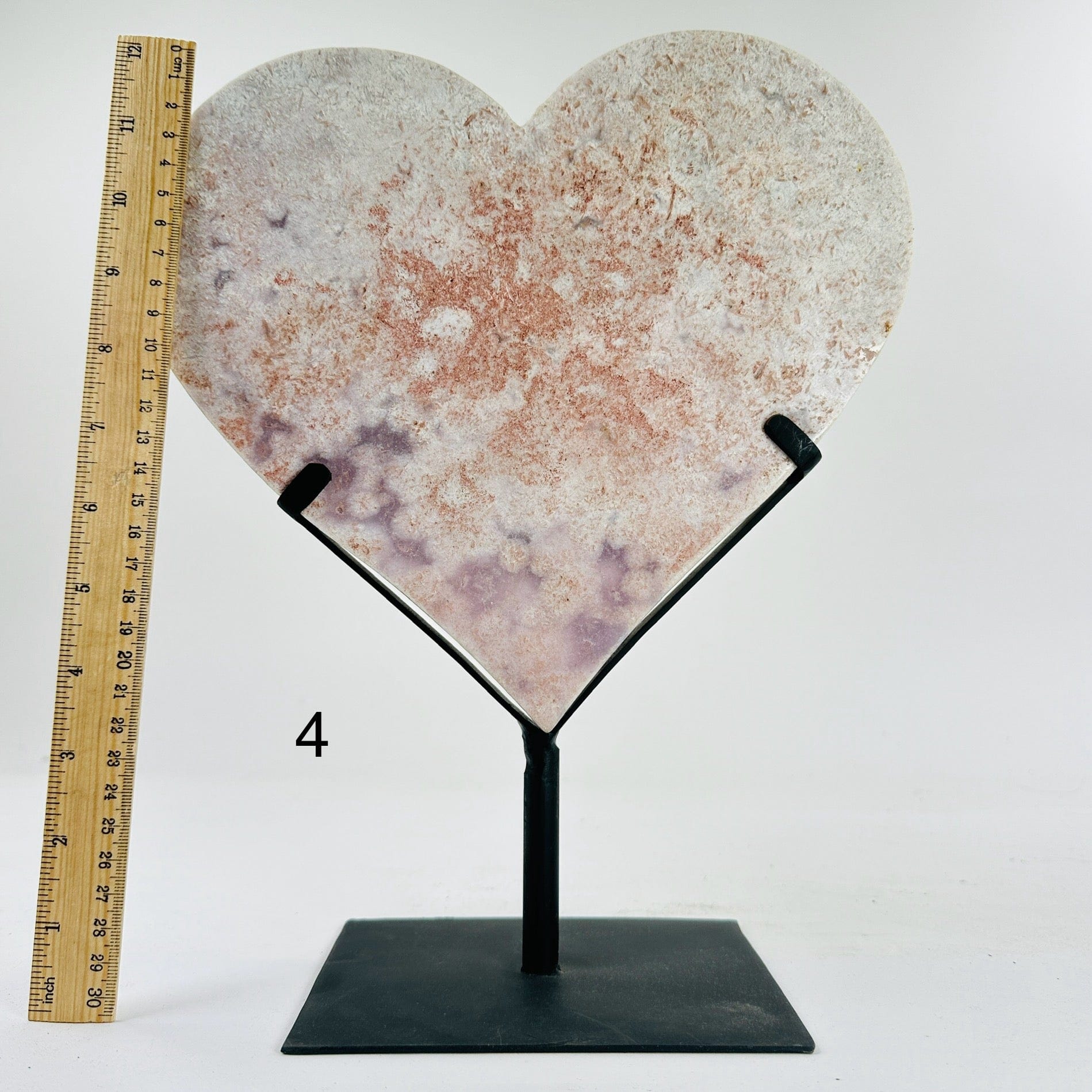 pink amethyst heart on metal stand next to a ruler for size reference