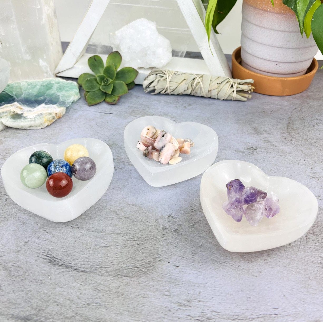 3 Selenite Heart Bowls at an angle, with stones inside