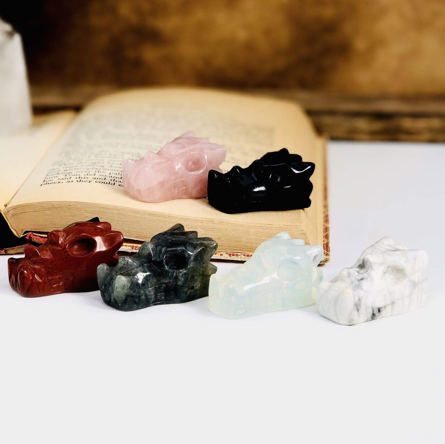 Side Angle of 6 Different Dragon Head Mini Statues on White Background.