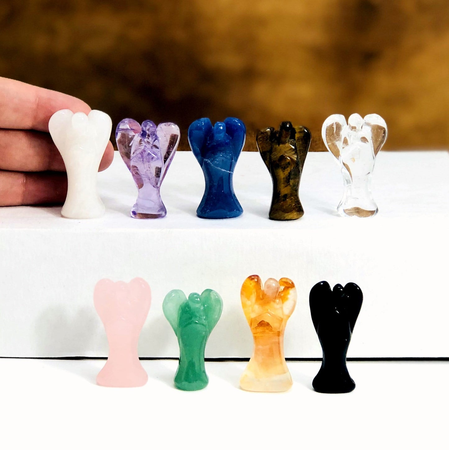 Gemstone angels displayed with hand on the side for size reference