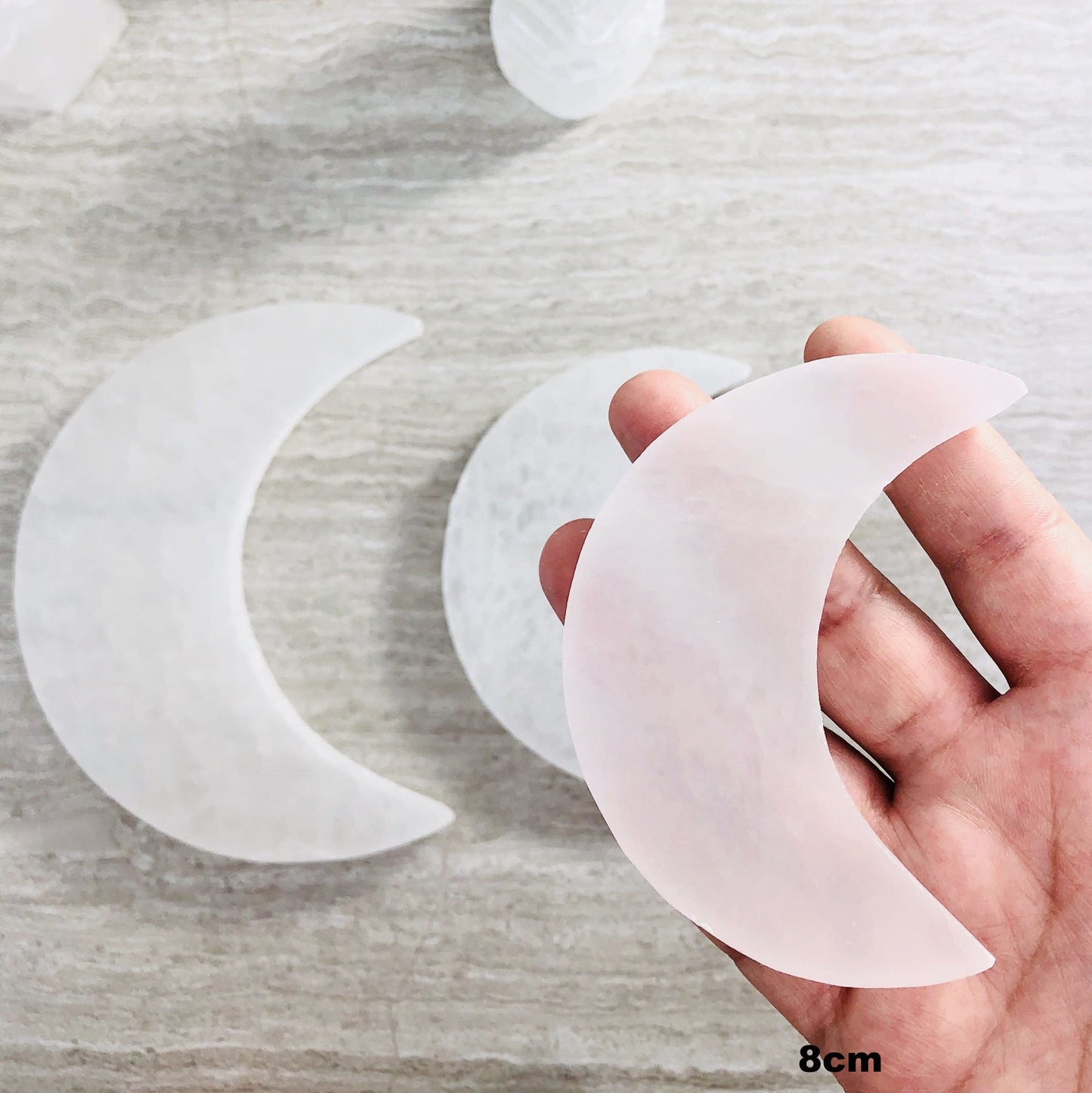 Selenite Moon Slice in hand for size reference. showing the 8cm moon