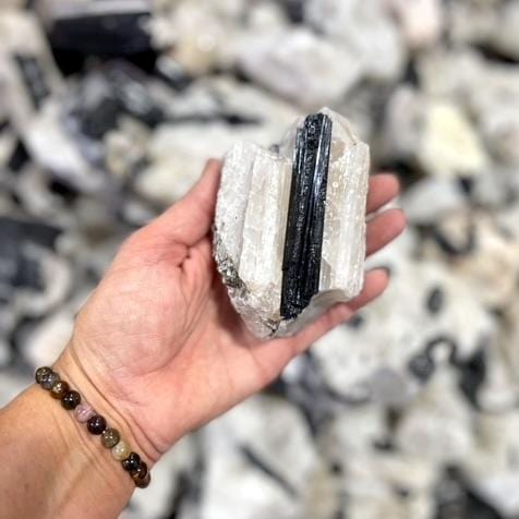 medium tourmaline on matrix in hand for size reference
