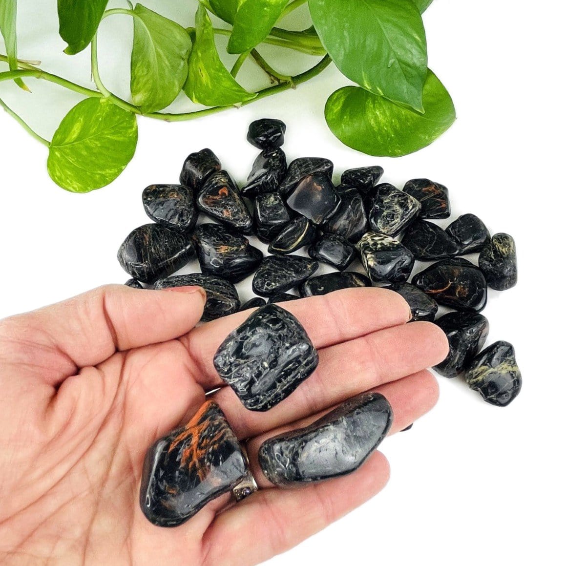 one pound of black tourmaline with red hematite tumbled stones in hand for size reference 
