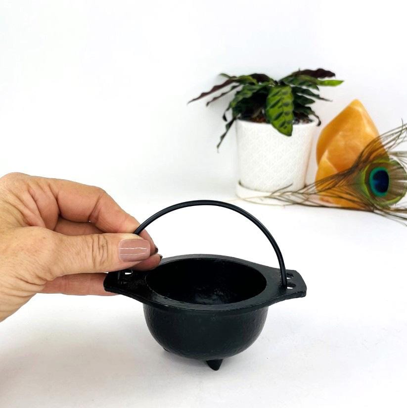 Hand holding the handle of the Black Cauldron 