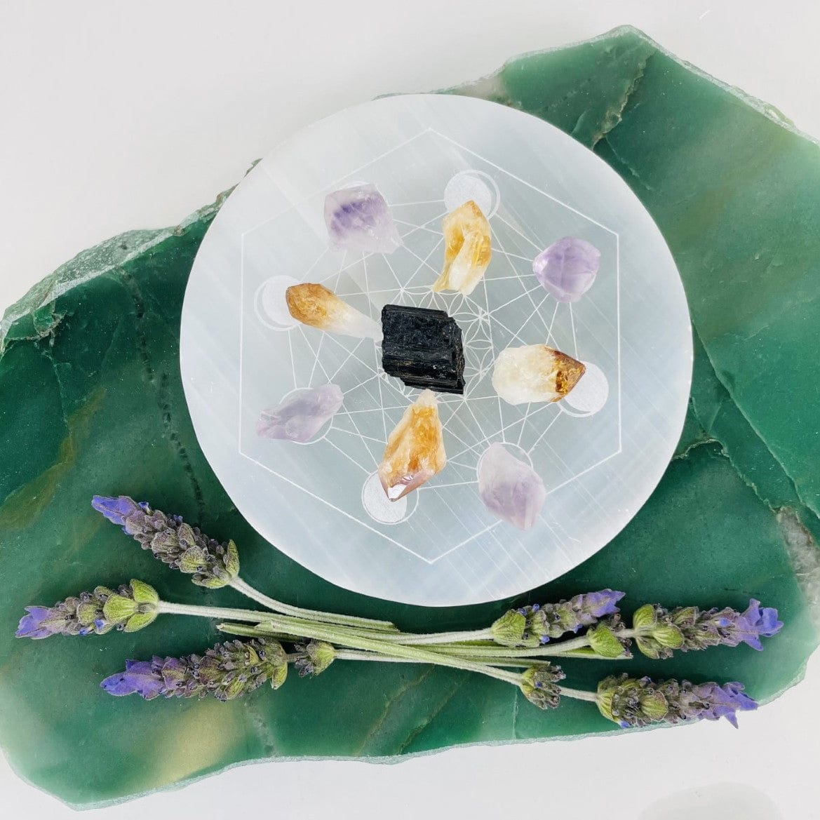 overhead view of selenite moon phase engraved charging plate with stones