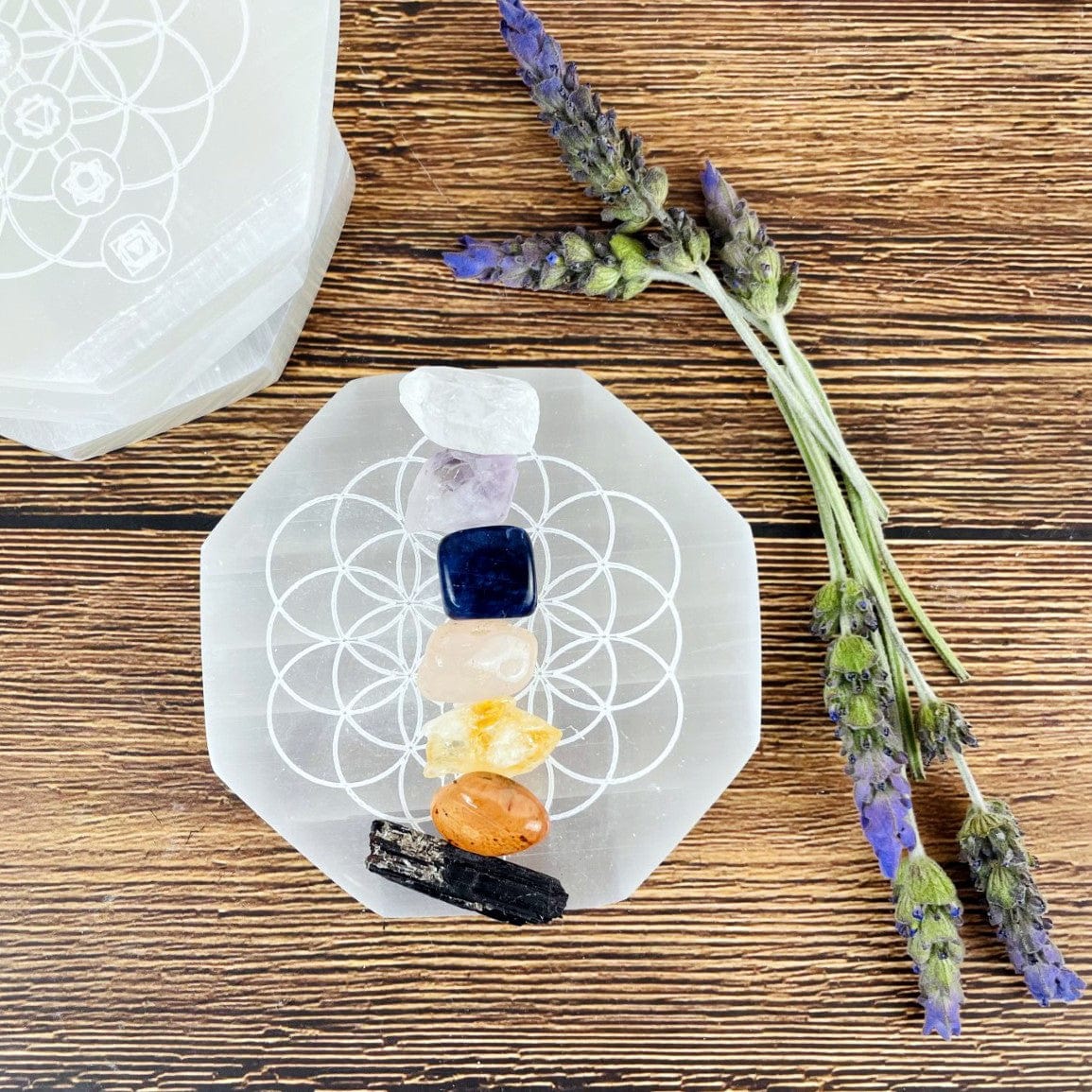 overhead view of selenite hexagon engraved with flower of life chakras with stones for approximate size reference