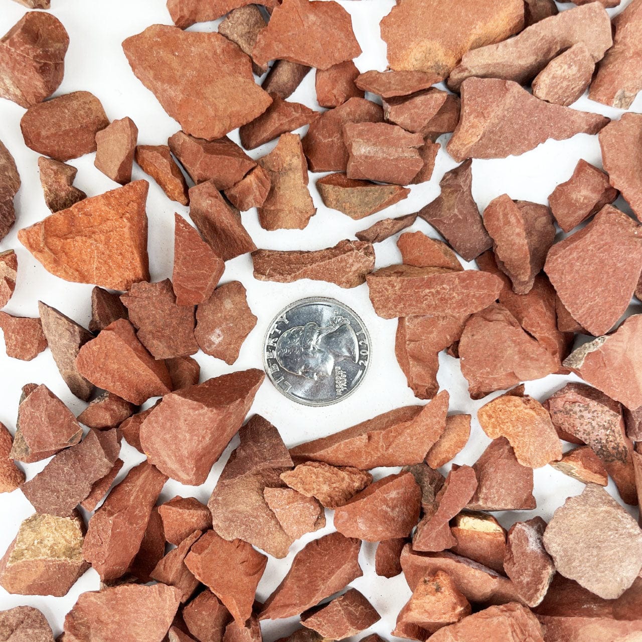 Red Jasper Stones spread on a table with a quarter for size