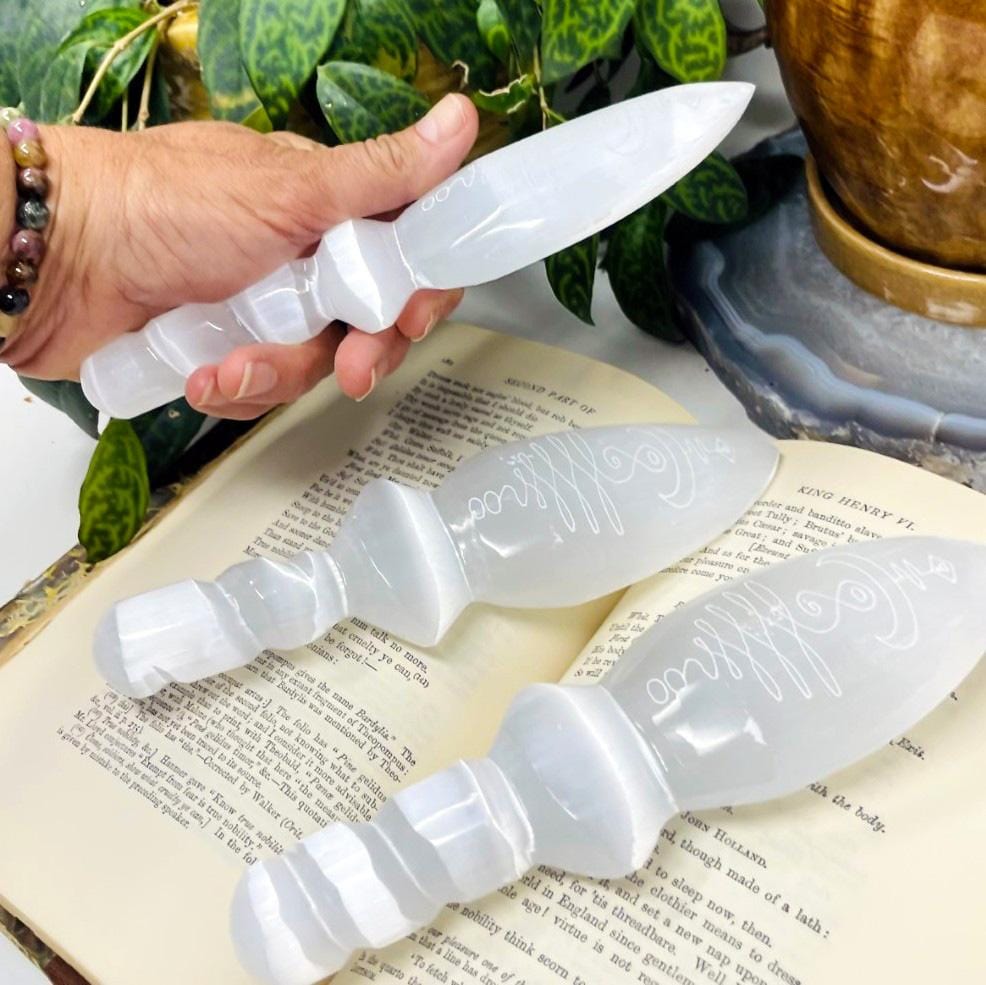 side view of selenite twisted handle knife with unalome engraving for thickness with others on display