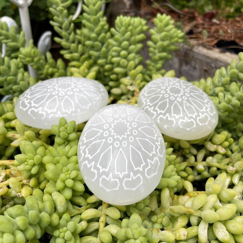 selenite mandala engraved palm stones on display