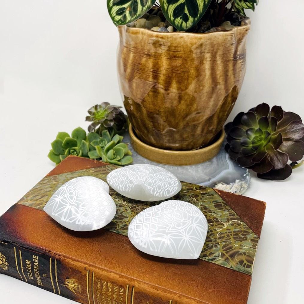three selenite stone hearts with eye engraving on display
