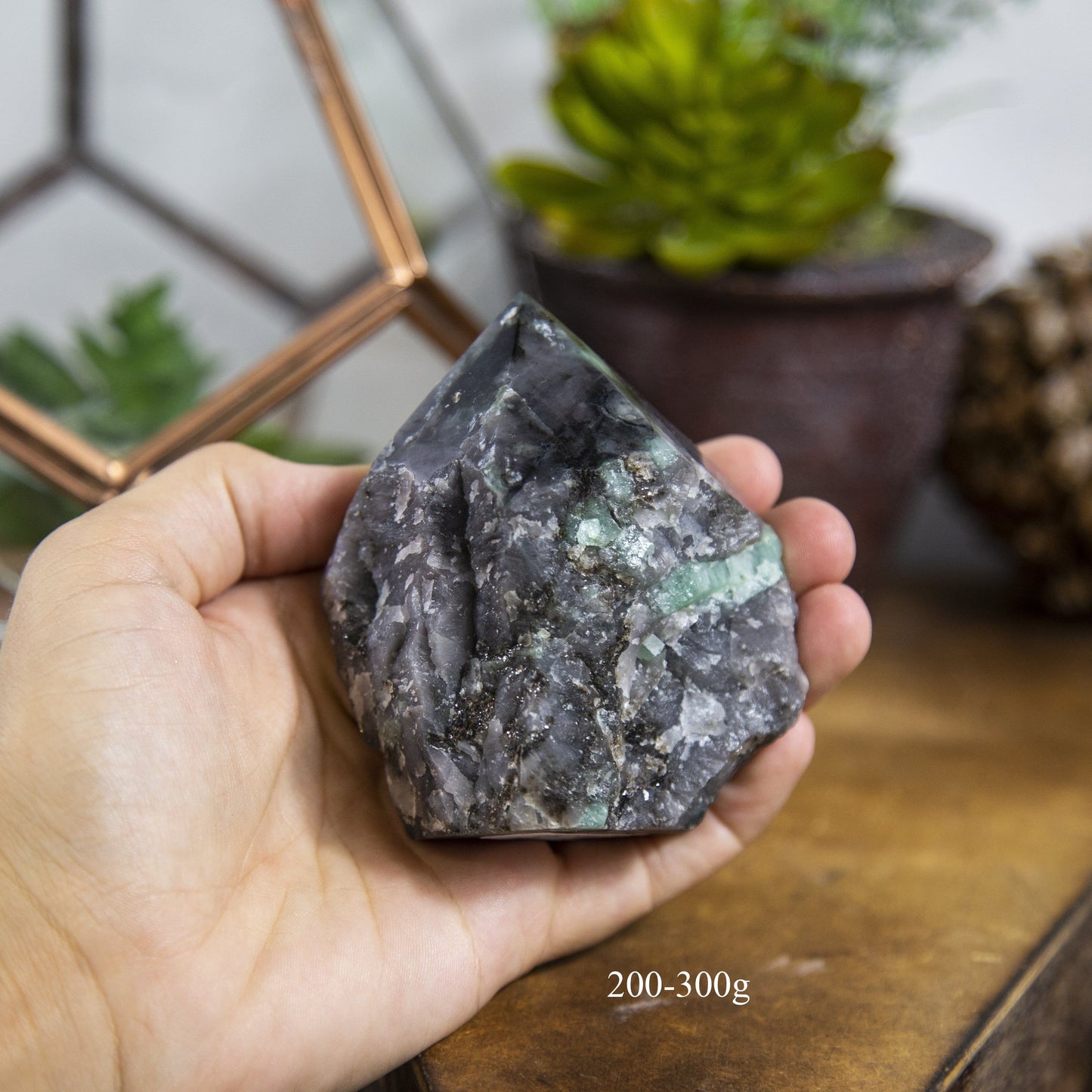 Semi Polished point Emerald Stone in hand showing the weight of 200 to 300g on white background