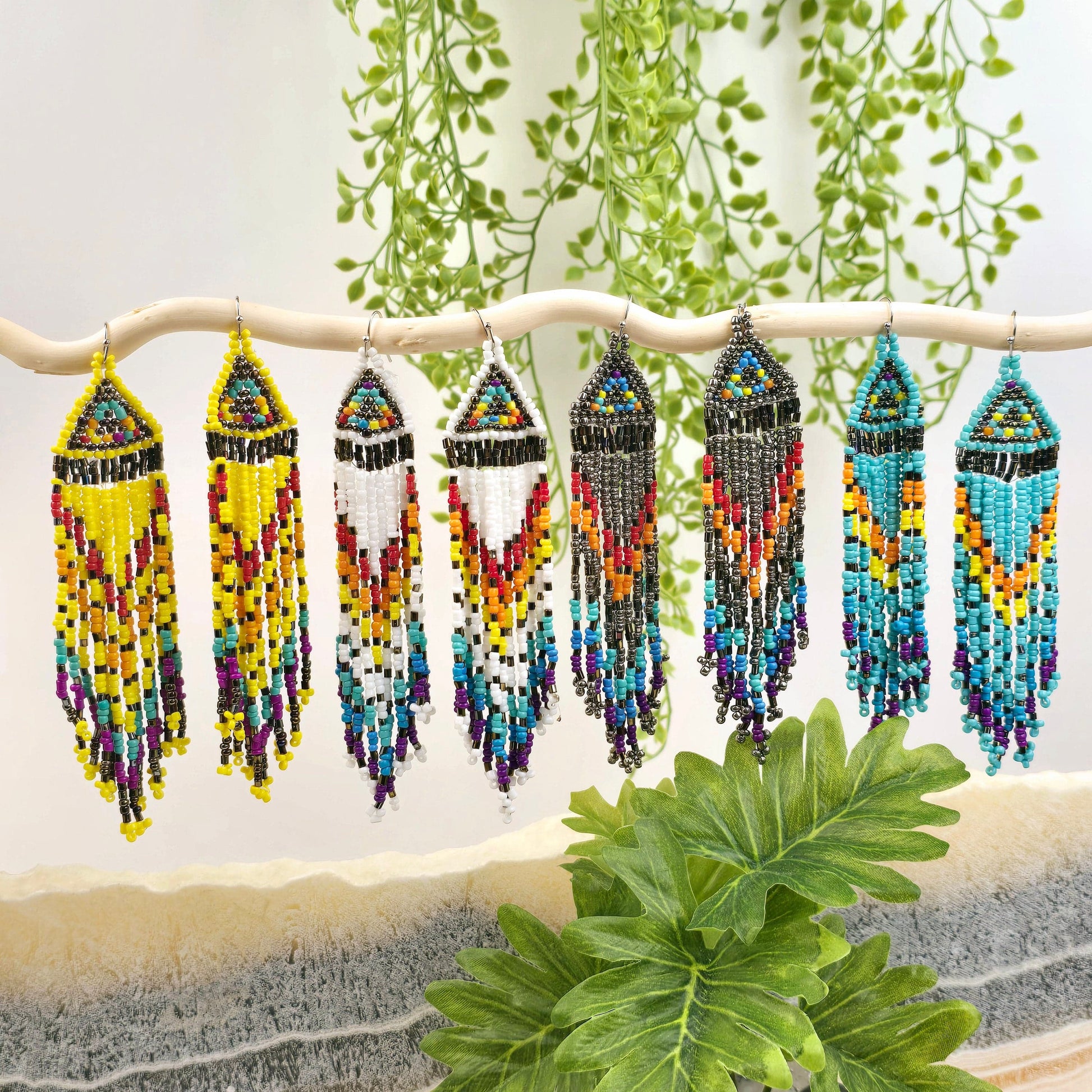 Seed Bead Earrings - Small Triangle Long Fringe Pattern - You Choose Style - all four styles on white branch with props and plants in the background