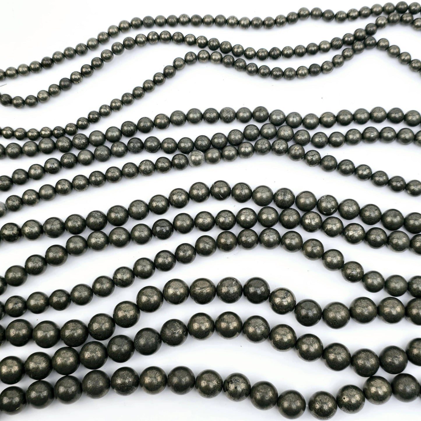 Pyrite Round Drilled Beads - 15.5" Strand - You Choose Size all sizes three of each strand lying horizontally on white surface