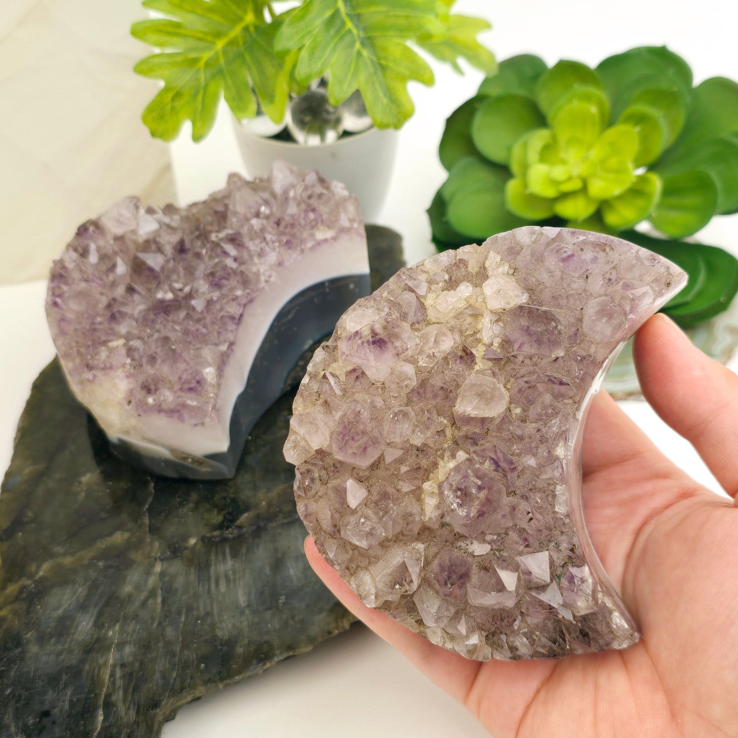 Agate Amethyst Polished Crystal Moon - You Choose variant 1 in hand for size reference with props and plants in the background