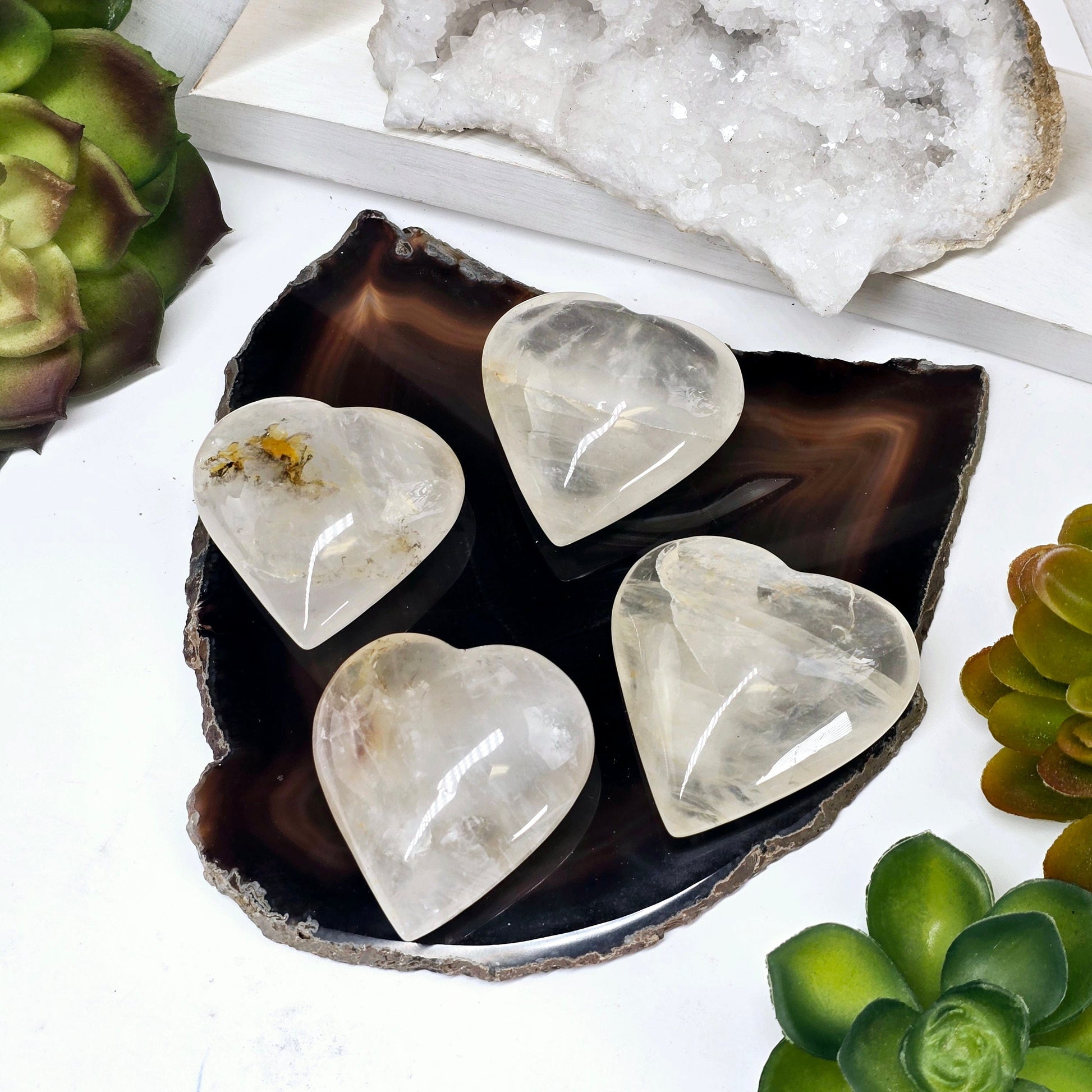 Golden Healer Small Polished Crystal Heart - You Choose #1 all variants on agate coaster with props and plants in the background