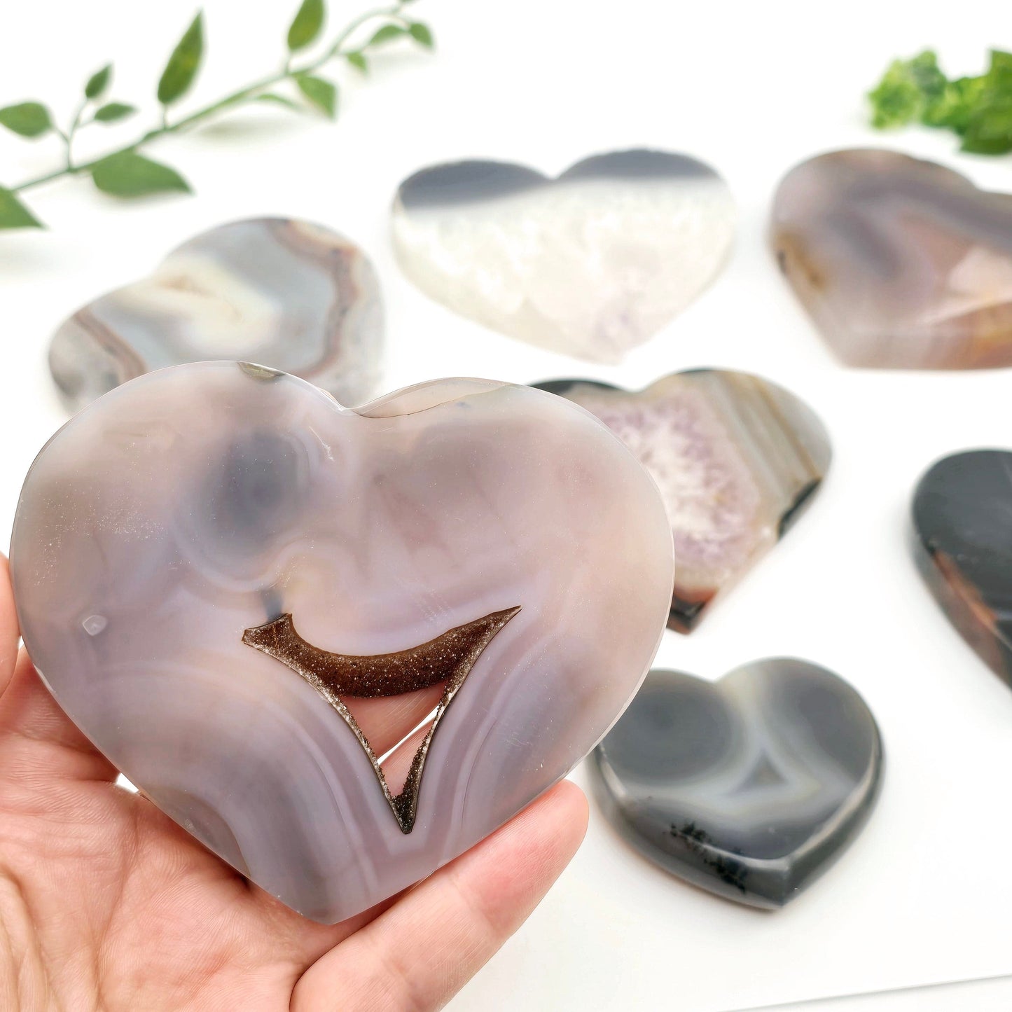 Agate Crystal Heart YOU CHOOSE Valentine's Day Gift Idea #3 one variant in hand for size reference with other variants in the background with plants