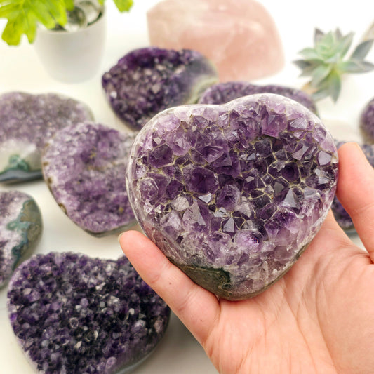 Amethyst Crystal Heart - You Choose #3 variant 10 in hand with other variants in the background with props and plants