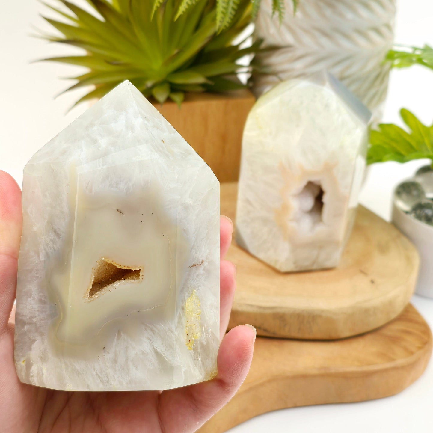 Agate Druzy Geode Polished Crystal Point - You Choose #2 variant 1 in hand for size reference with other variant in background with props and plants