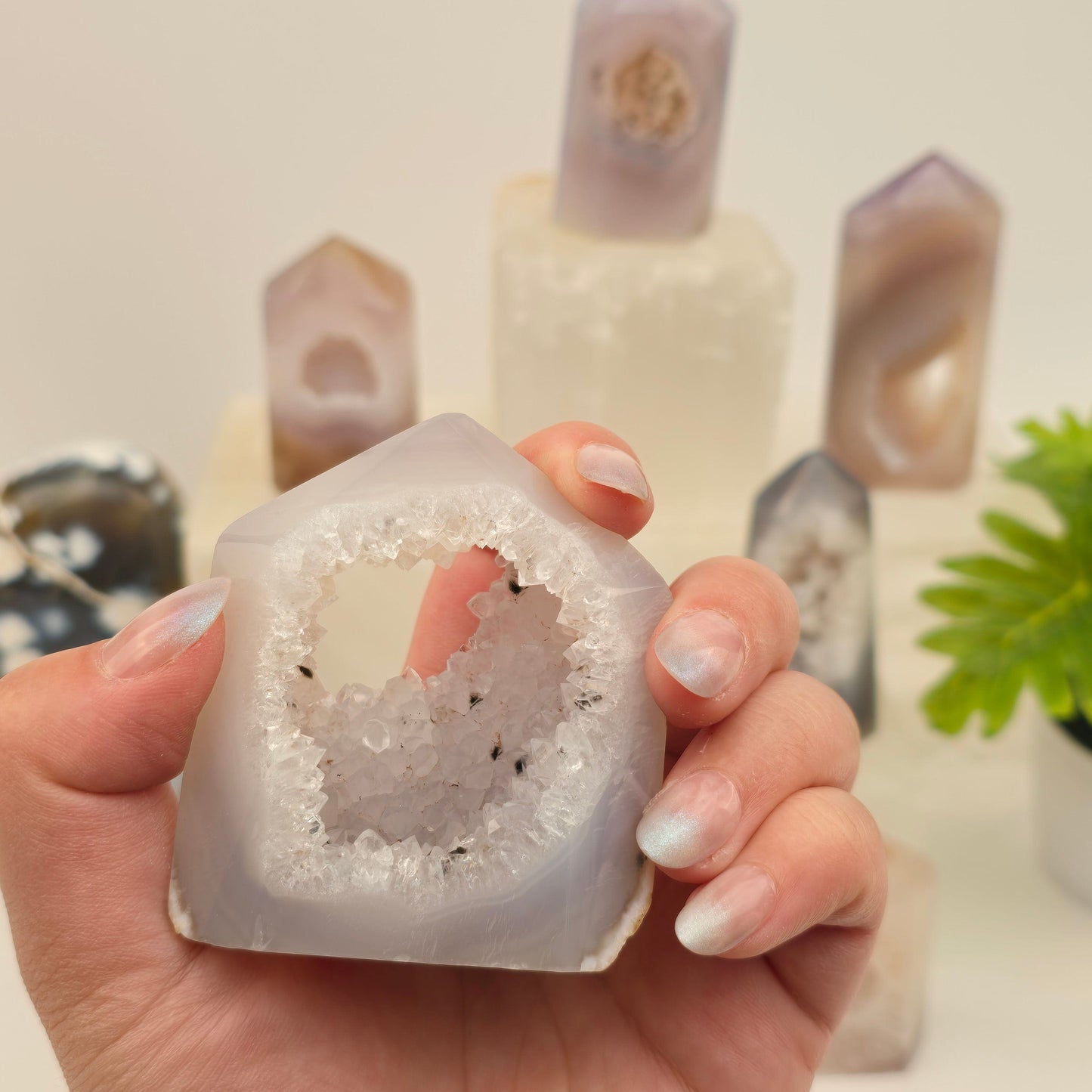 Agate Druzy Geode Polished Crystal Point - You Choose #3 variant 2 in hand for size reference with other variants in the background with props and plants