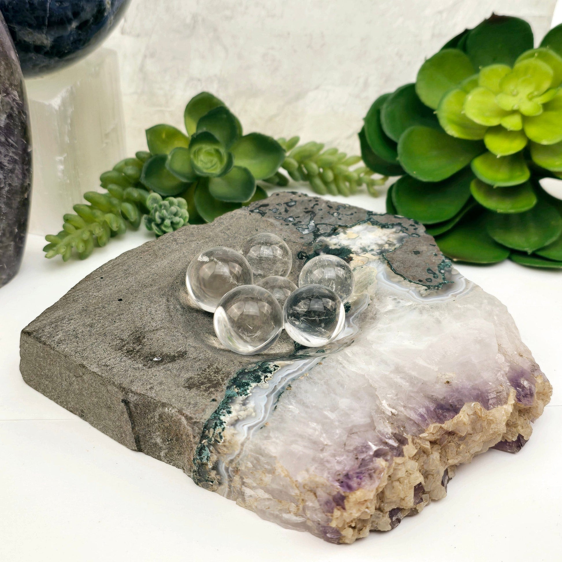 Amethyst and Calcite on Matrix Semi Polished Crystal Bowl #1 with small crystal quartz spheres in the bowl with plants and props in the background