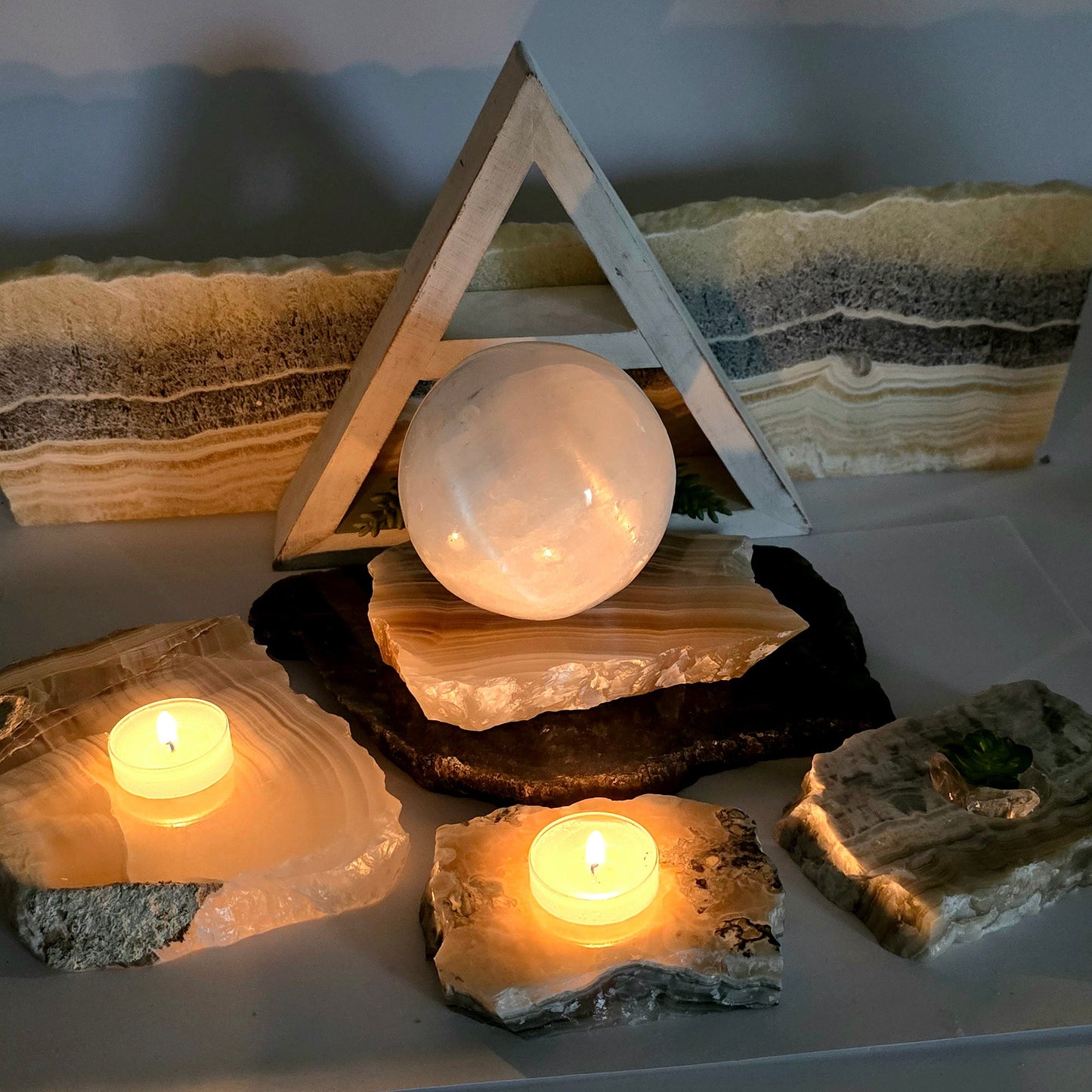Grey Travertine Calcite - Grey Onyx - Crystal Candle Holder - By Size both variants with props and plants in the background dark with candles lit