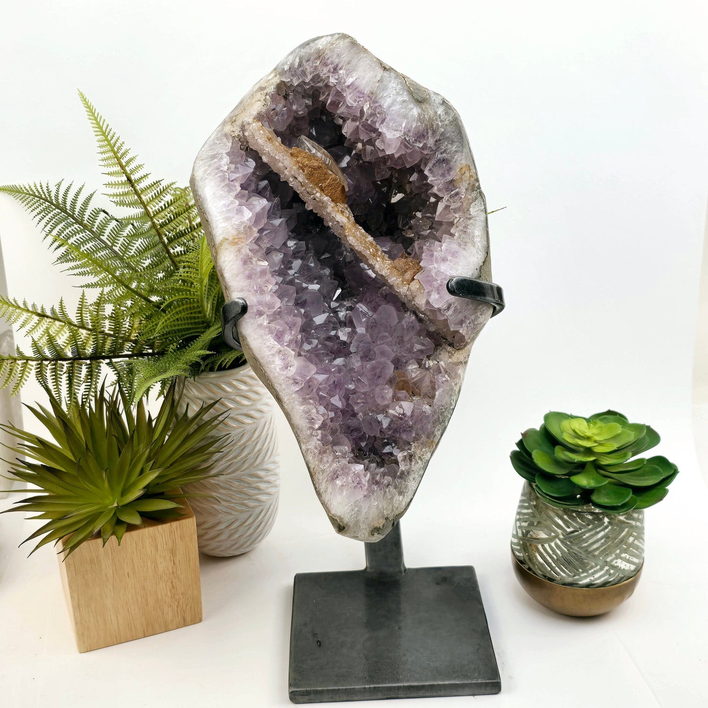 Amethyst Large Crystal Cluster with Druzy Stalactite and Double Terminated Calcite on Metal Stand front view with props and plants