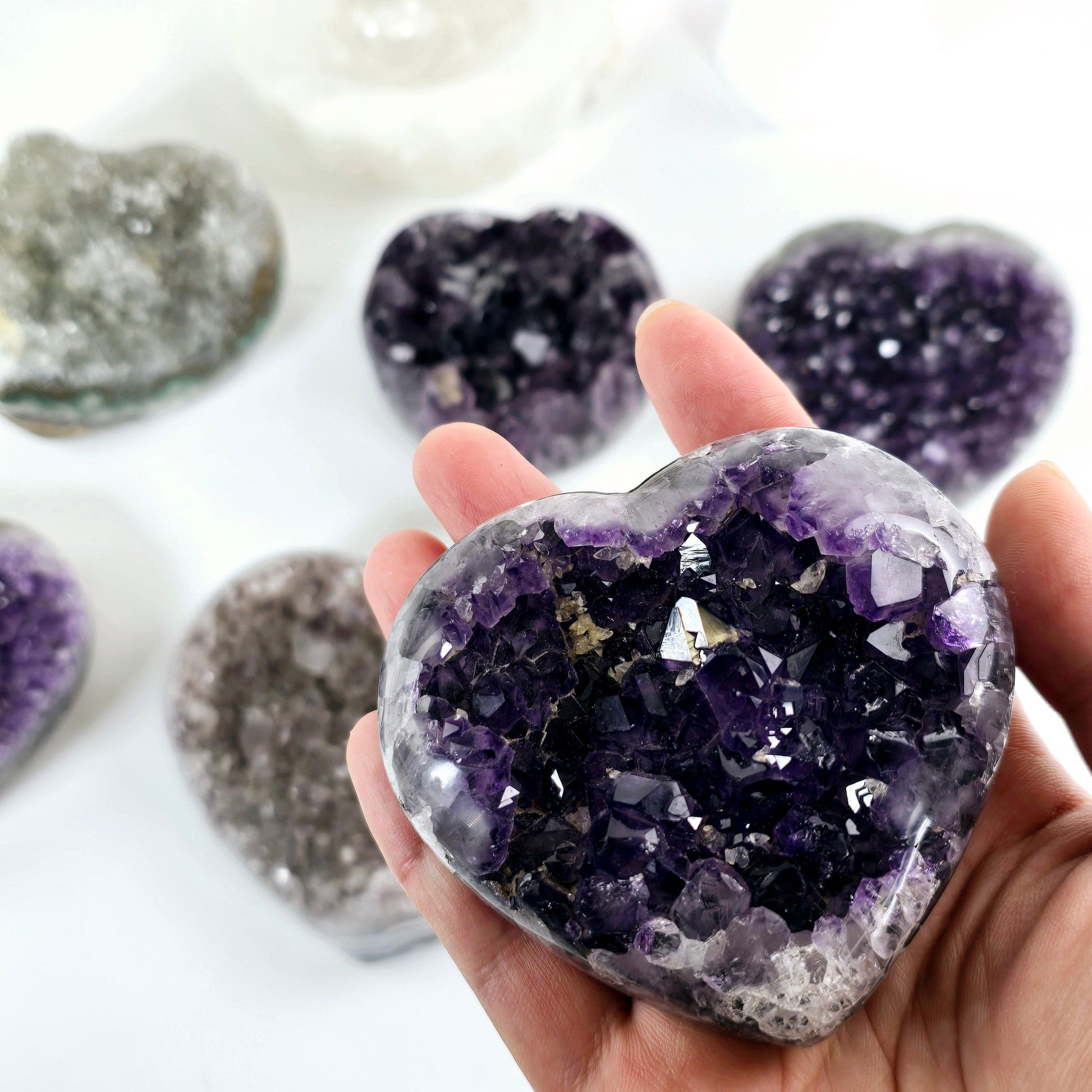 Amethyst Crystal Heart - You Choose #3 one variant in hand for size reference with other variants in background