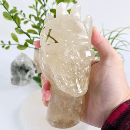 Natural Citrine with Epidote Crystal Hand Holding Skull Sculpture - One-of-a-Kind in hand for size reference with plants and props in the background
