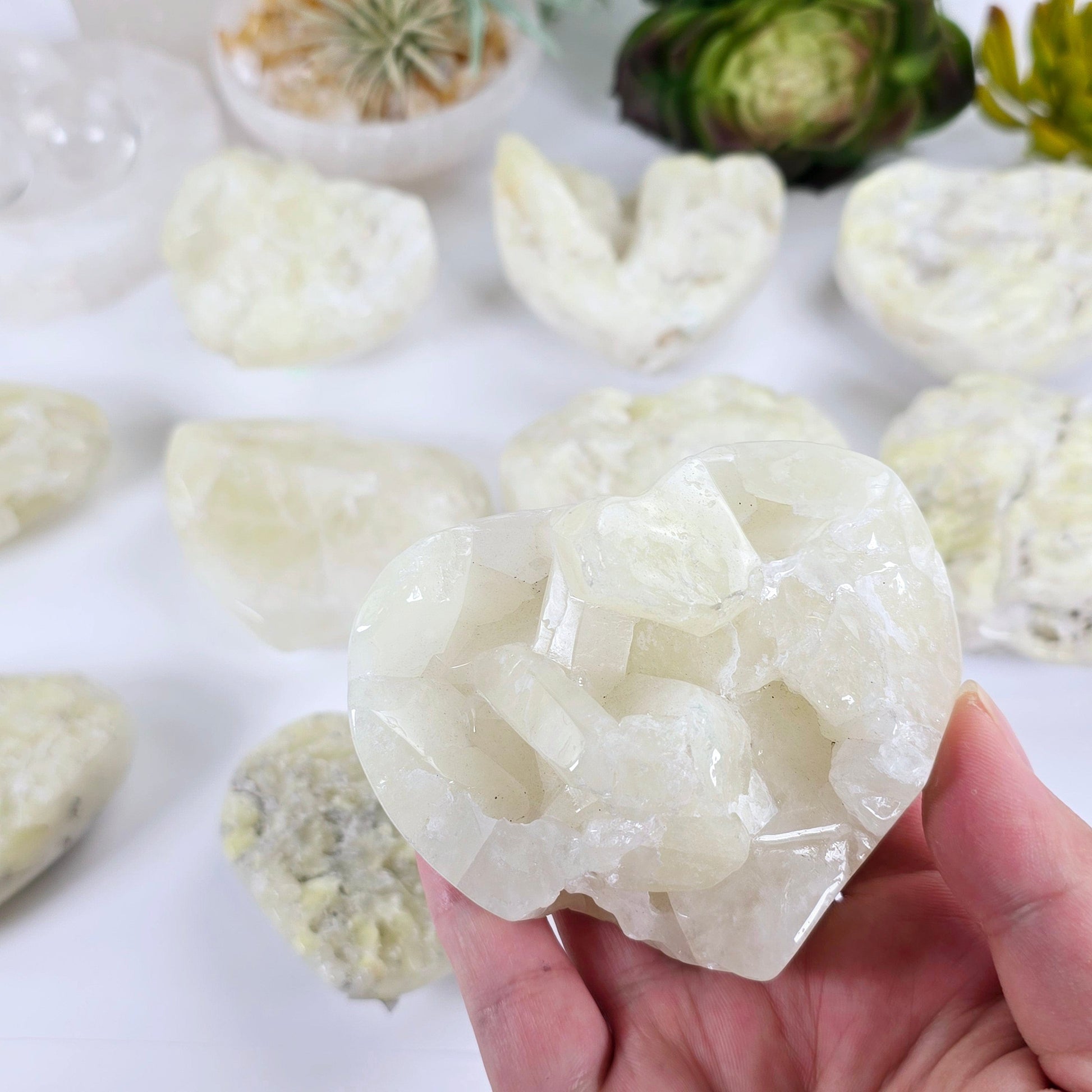 Sulfur Quartz Polished Crystal Cluster Heart - You Choose #2 variant 7 in hand for size reference with others in the background with props and plants