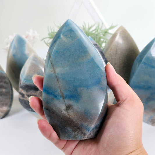 Trolleite Crystal Flame Point - You Choose #2 one variant in hand with other variants in the background with props and plants