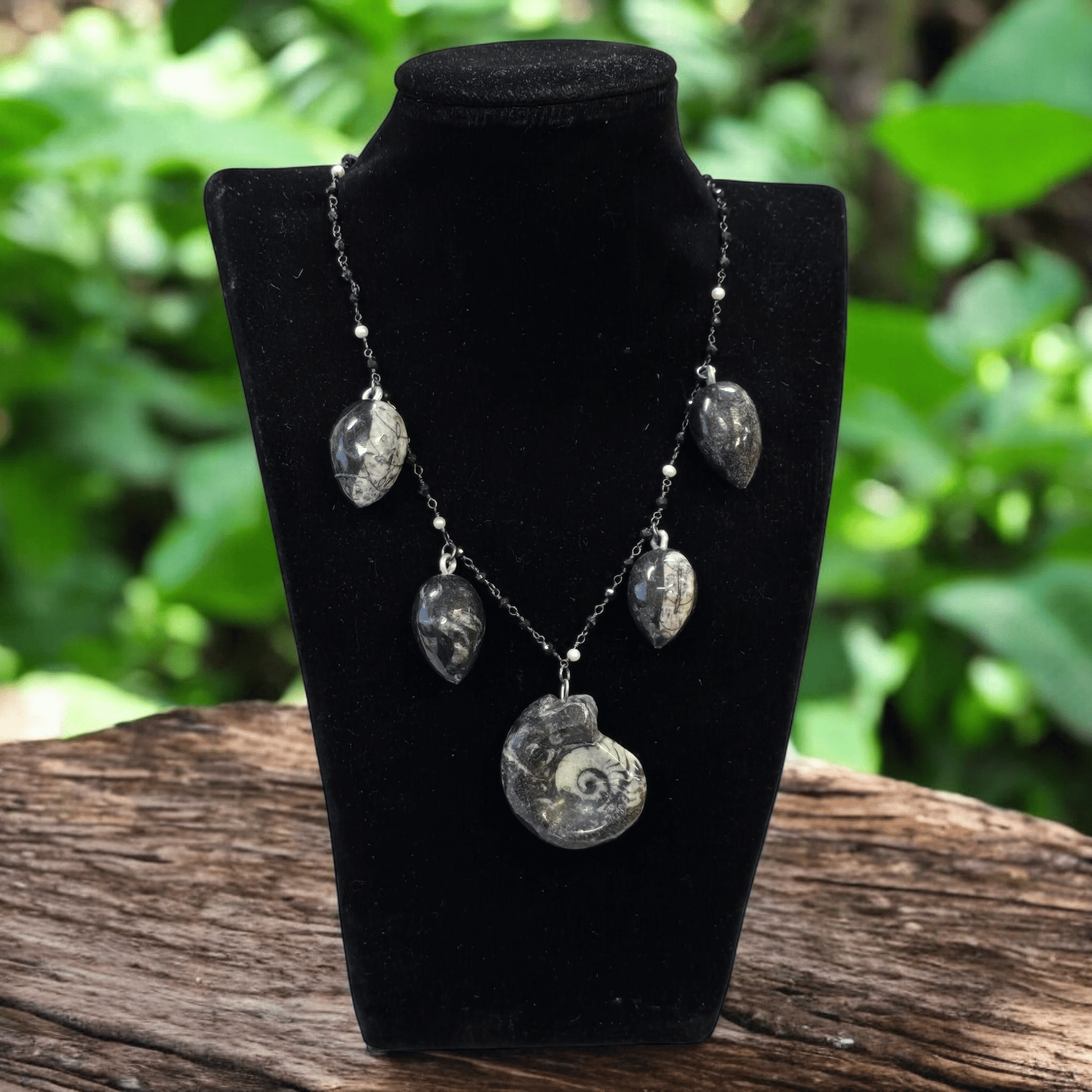 Ammonite and Orthoceras Fossil Charm Necklace with Black Spinel and Pearl Oxidized Sterling Silver Chain - Handmade on necklace stand with plants in the background