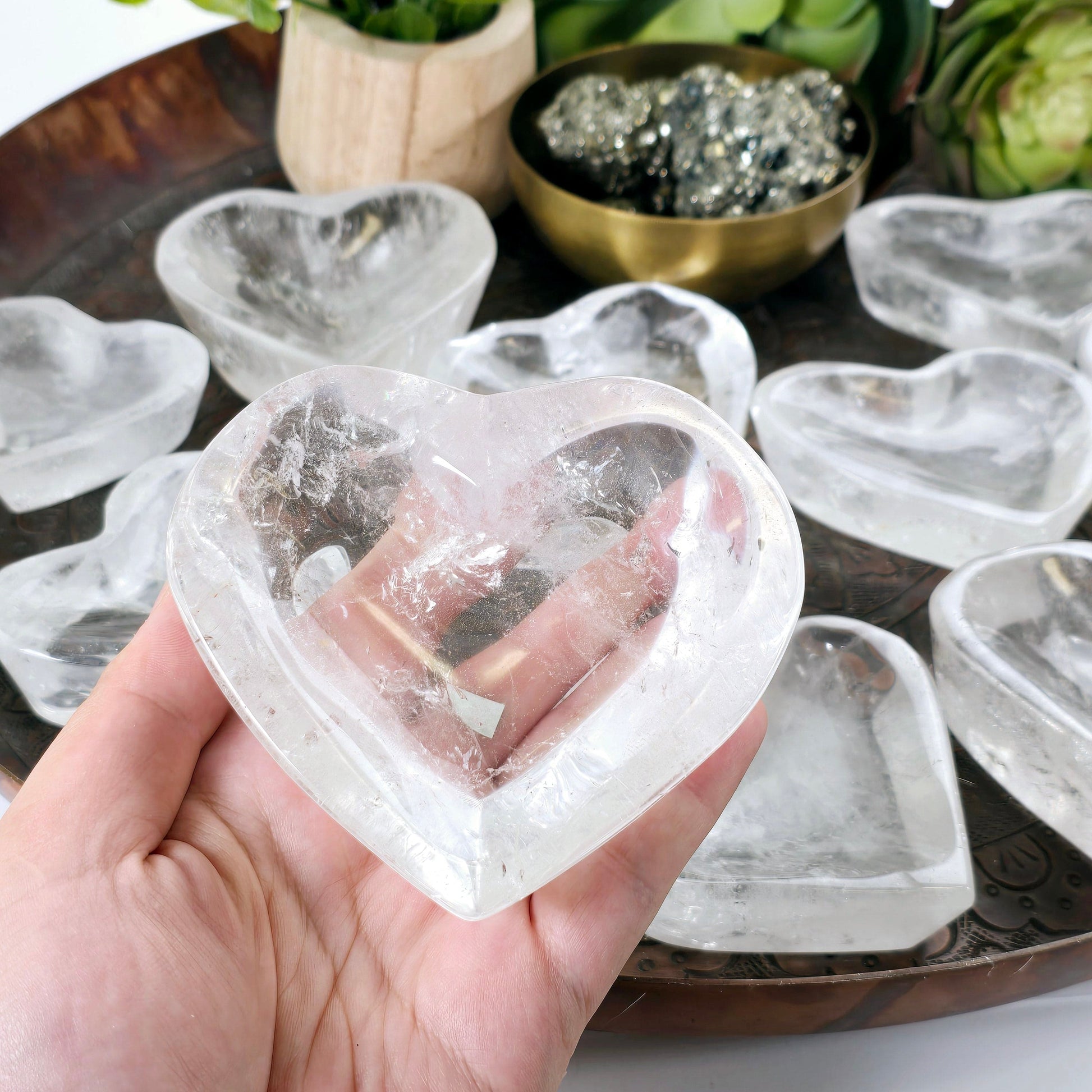 Crystal Quartz Heart Dish - You Choose #2 one variant in hand for size reference with other variants in the background with props and plants