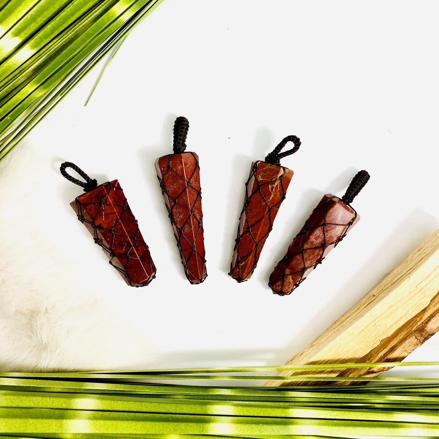 4 Red Jasper Points - Netted Pendants brown variant with dried plants on white background