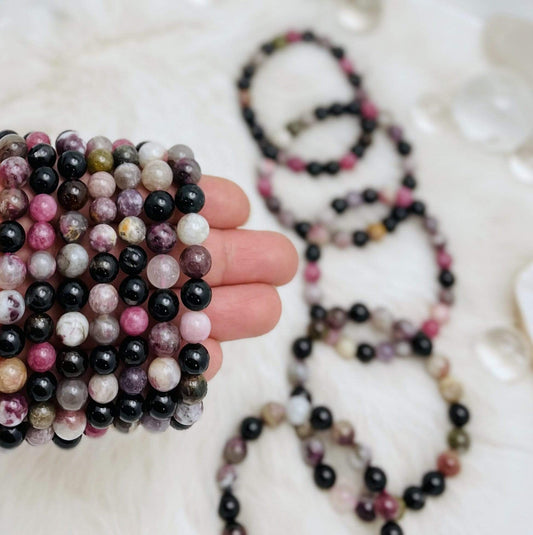 Several Products Watermelon Tourmaline Round Bead Bracelets in hand for size reference 