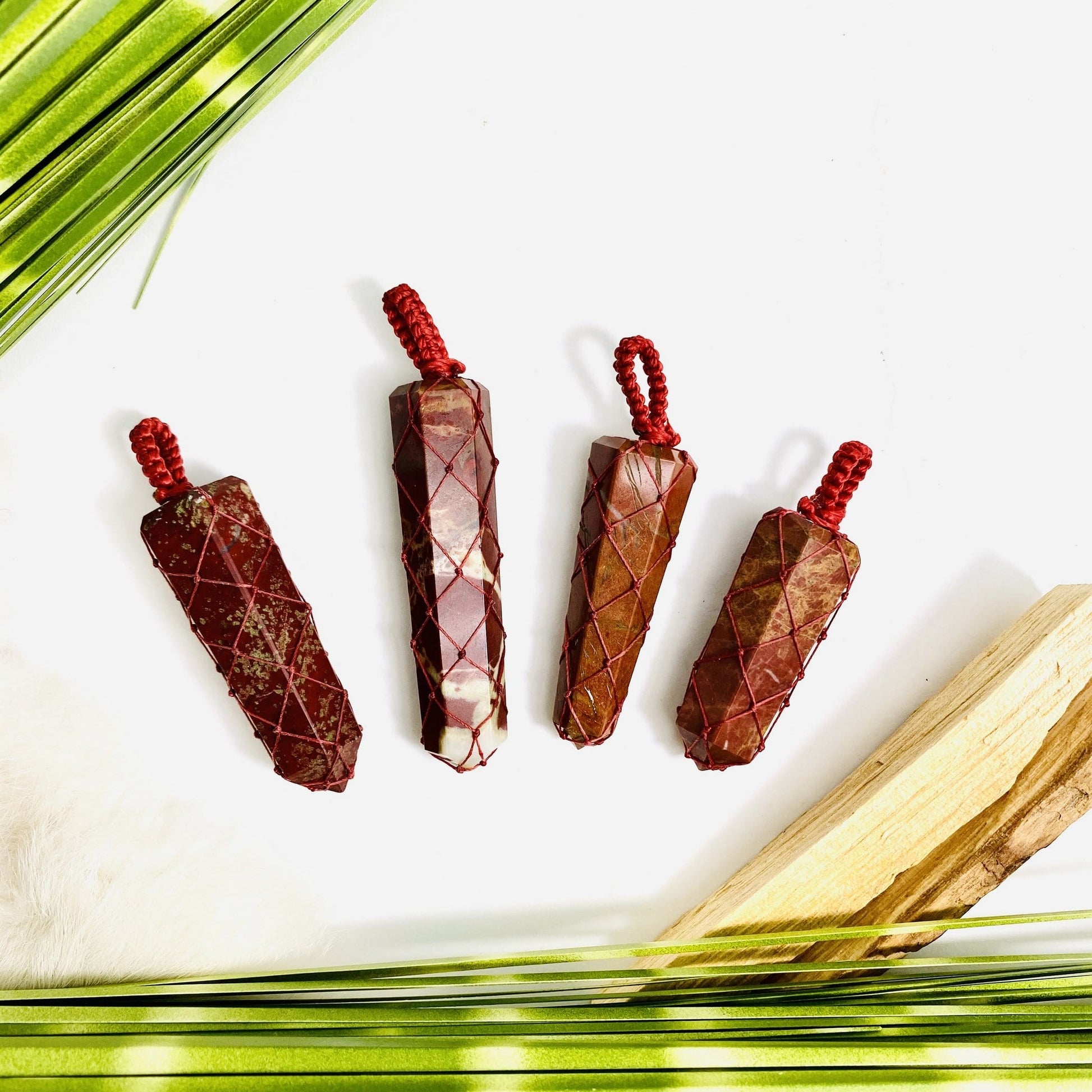4 Red Jasper Points - Netted Pendants red variant with dried plants on white background