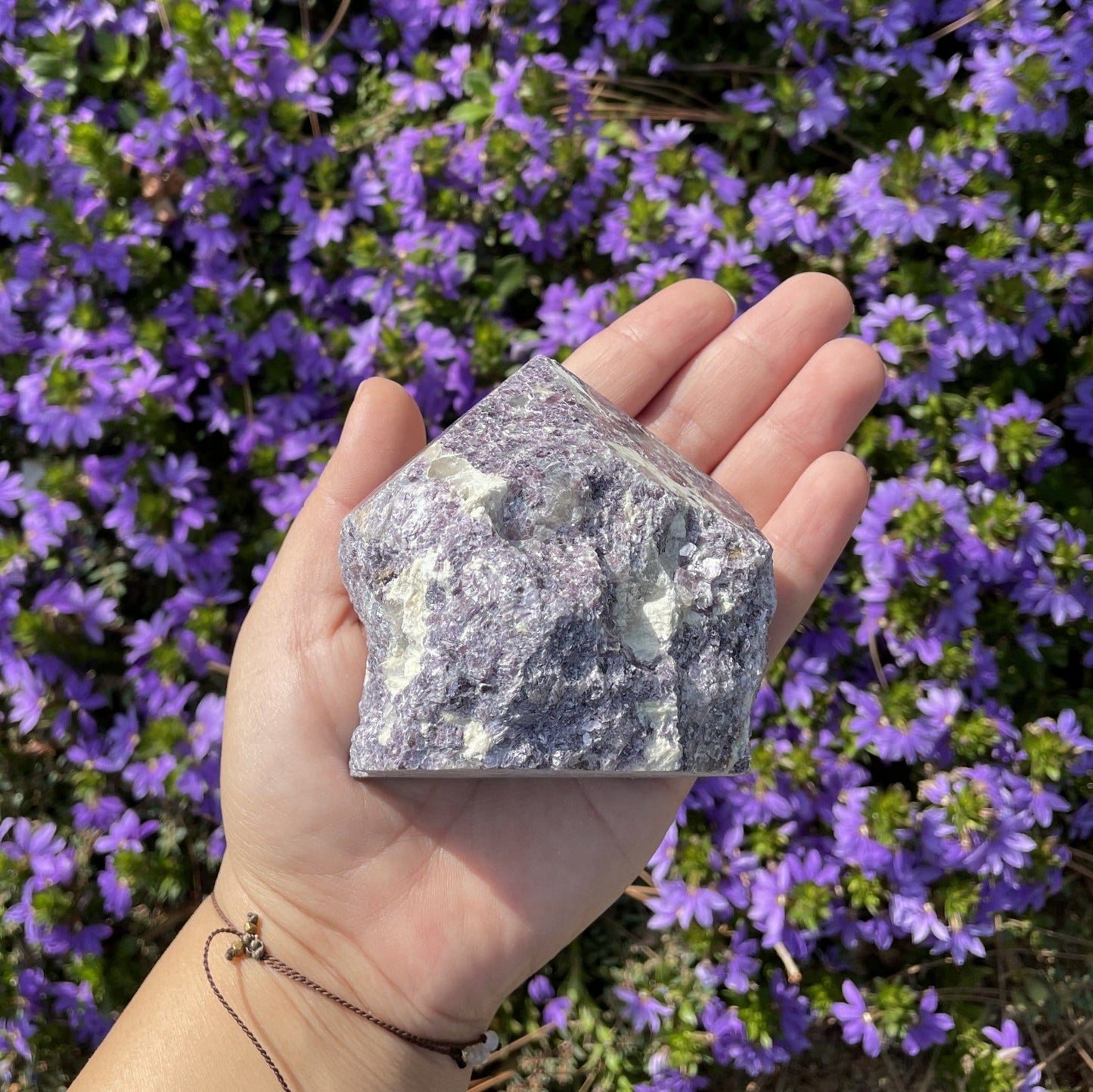 lepidolite semi polished point with decorations in the background