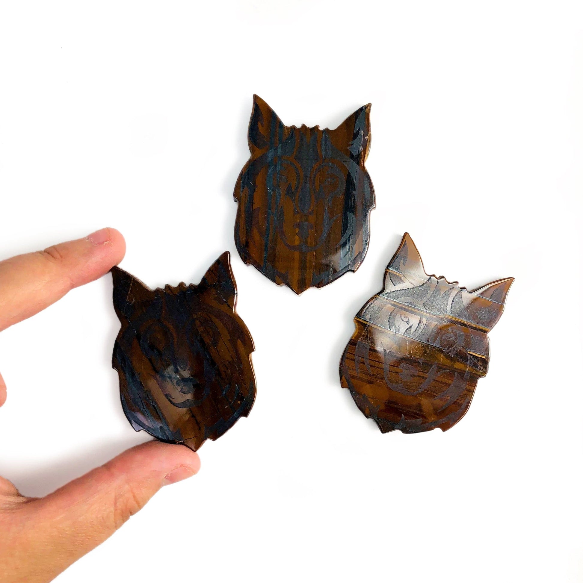 fingers holding Gemstone Wolf Slices with 2 others on white background