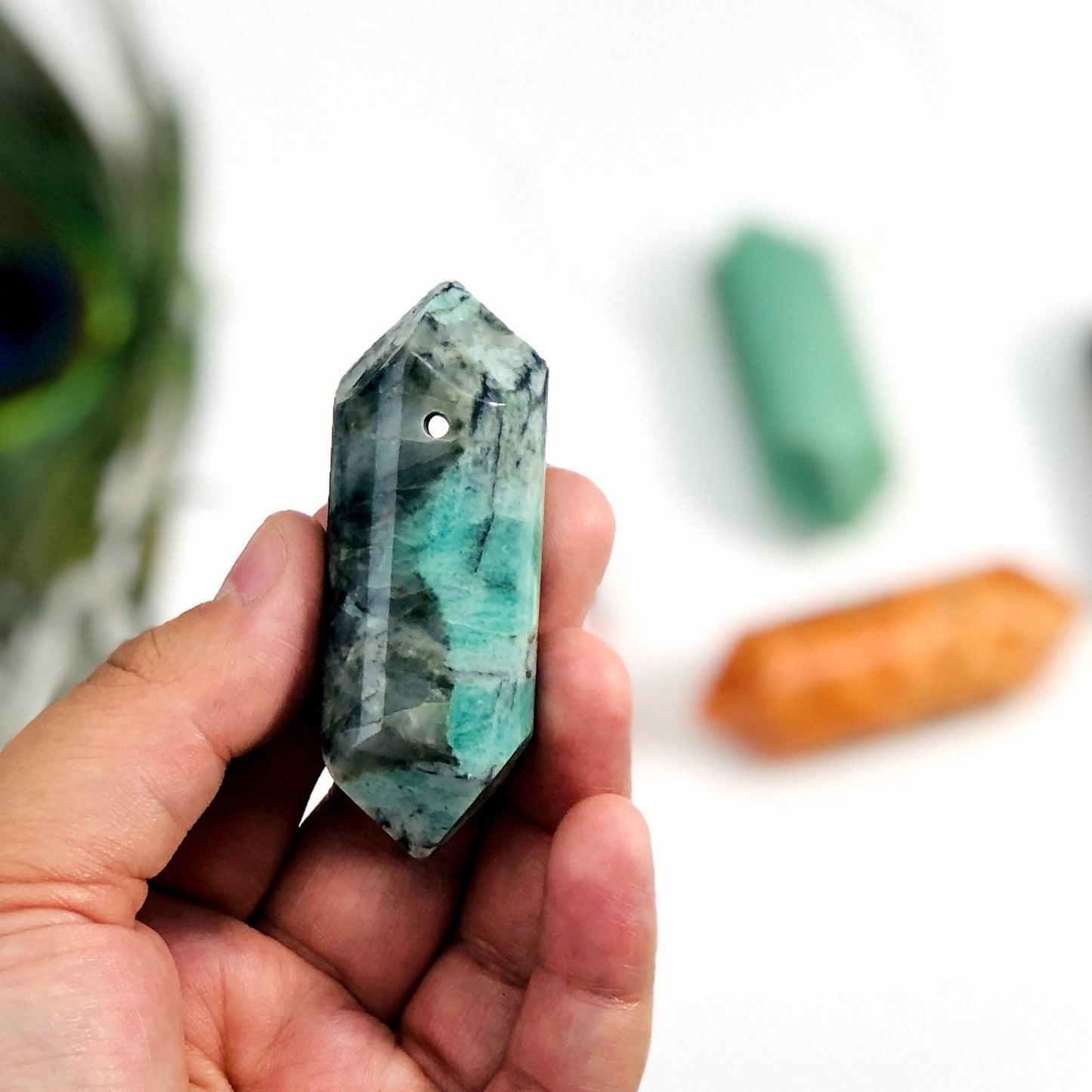 gemstone polished drilled point in hand for size reference 