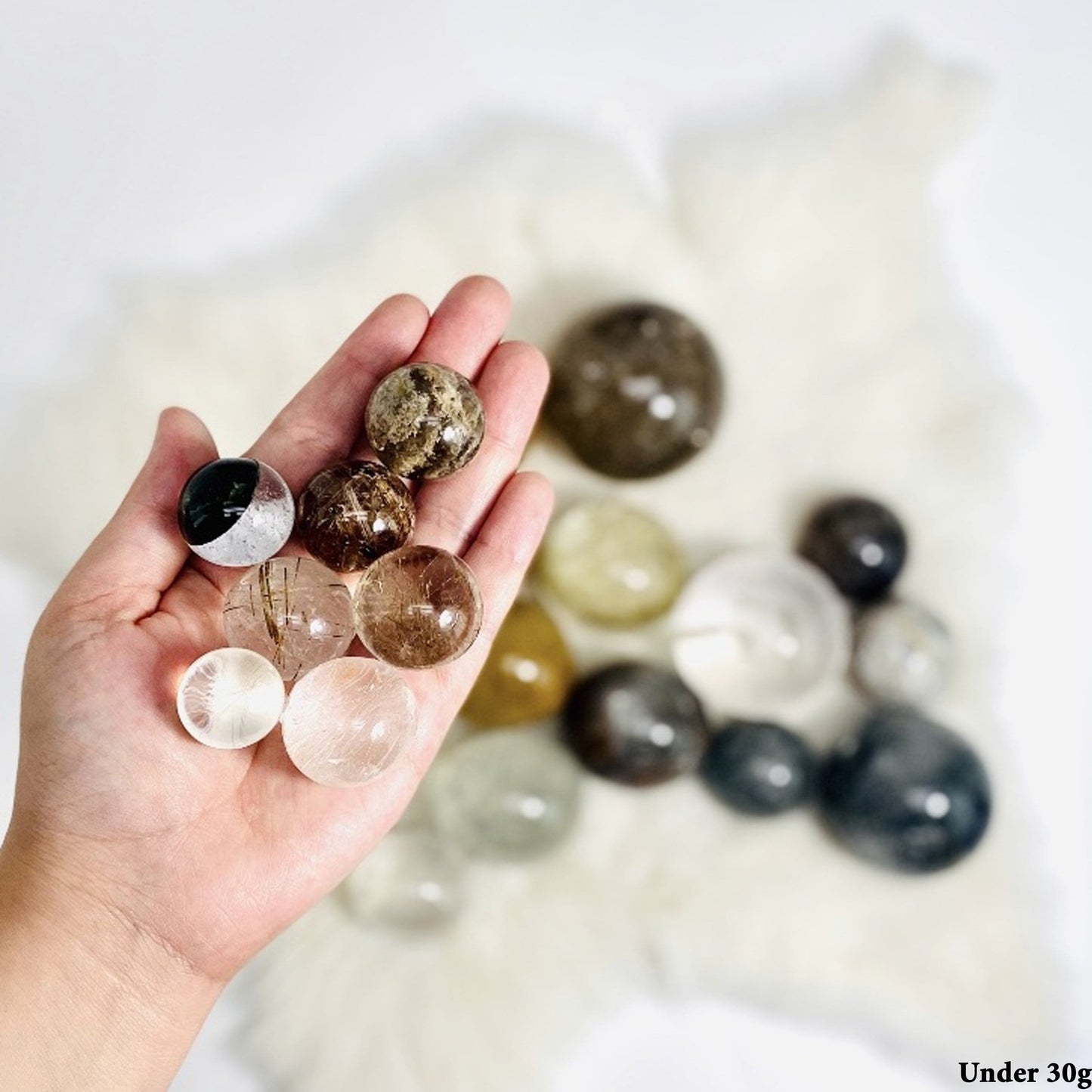 Assorted Quartz Spheres, under 30g, displayed in hand