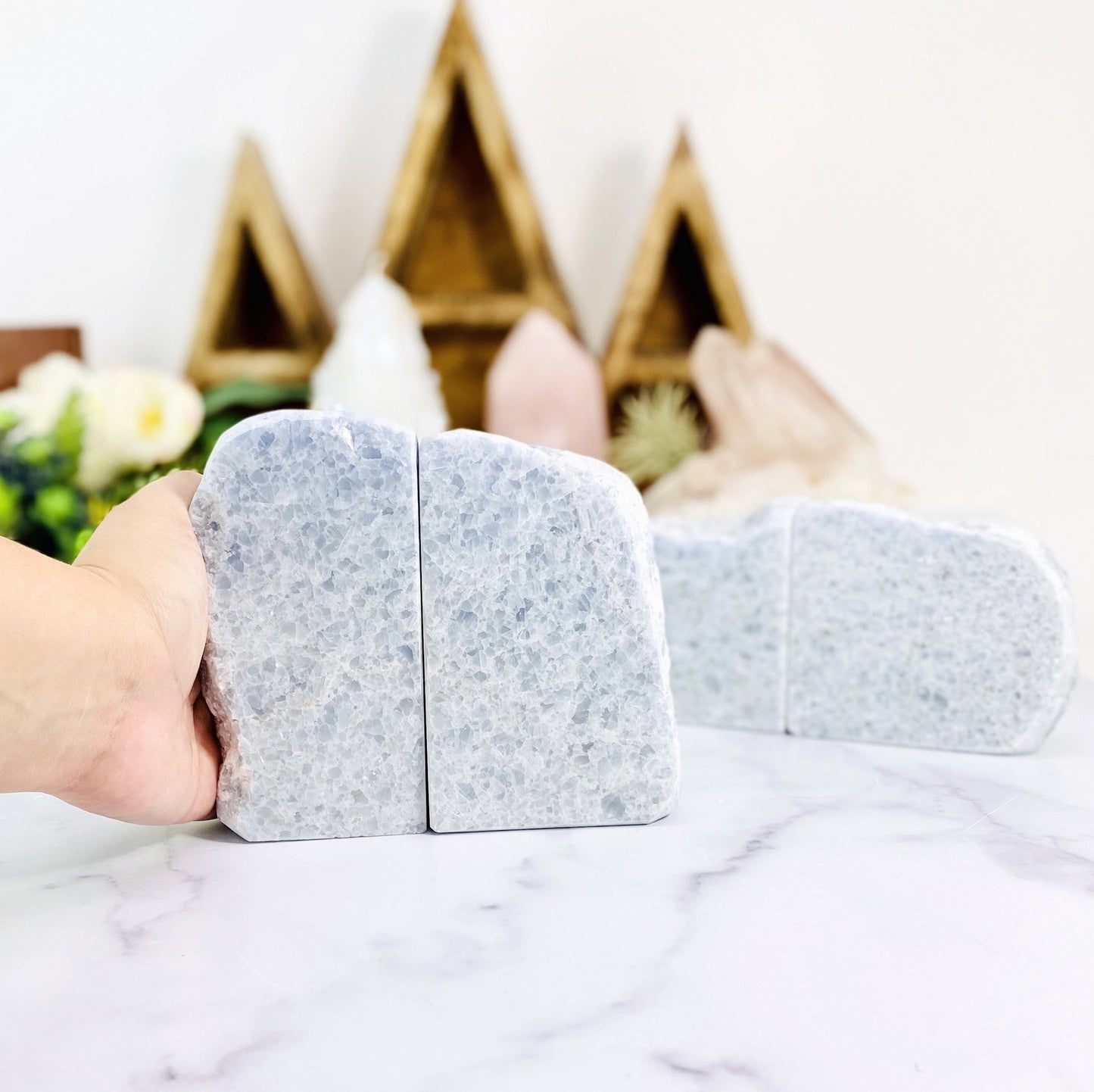 hand holding blue calcite bookends with other crystals blurred in the background